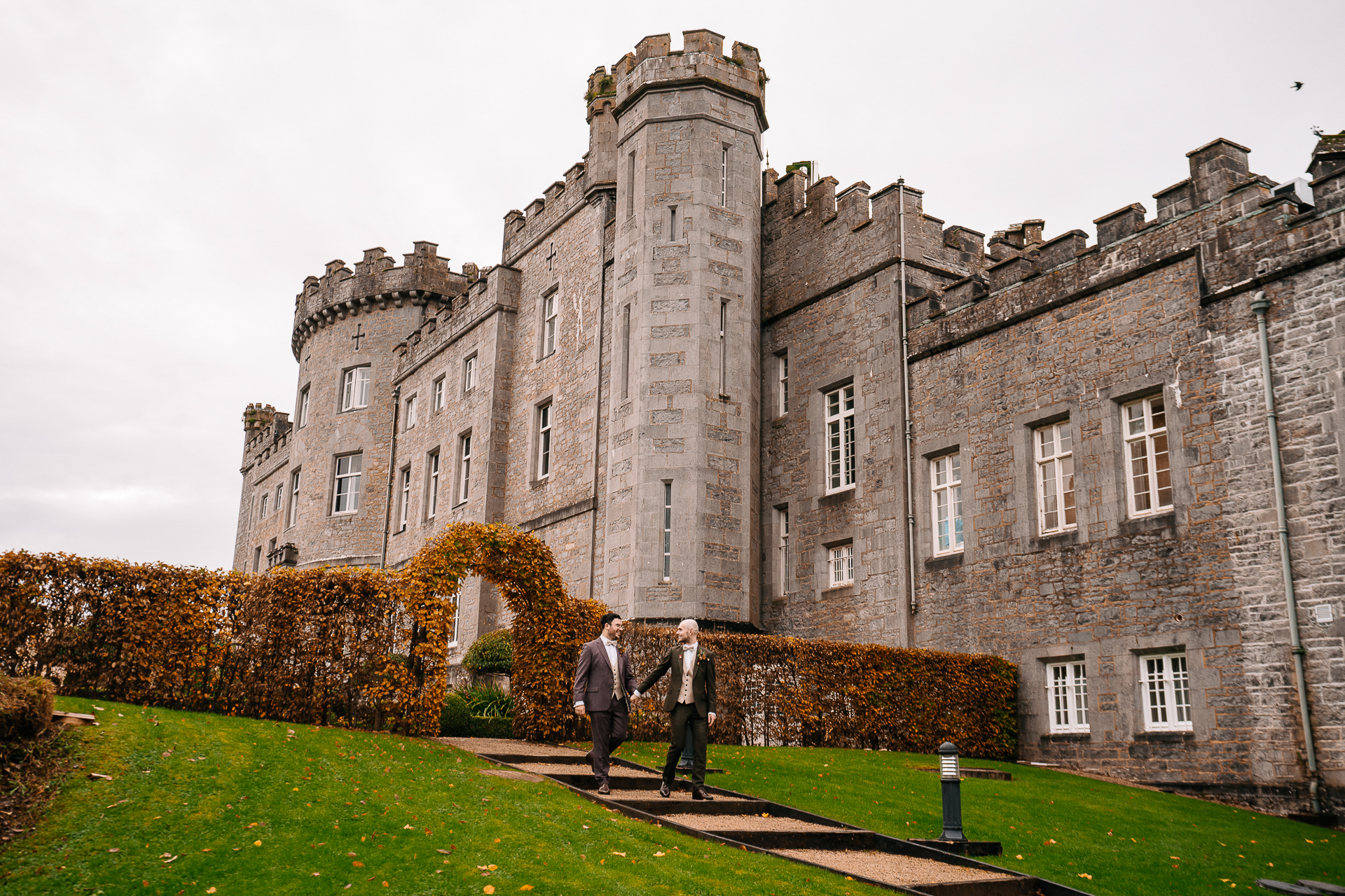 A couple of men standing in front of a large stone building