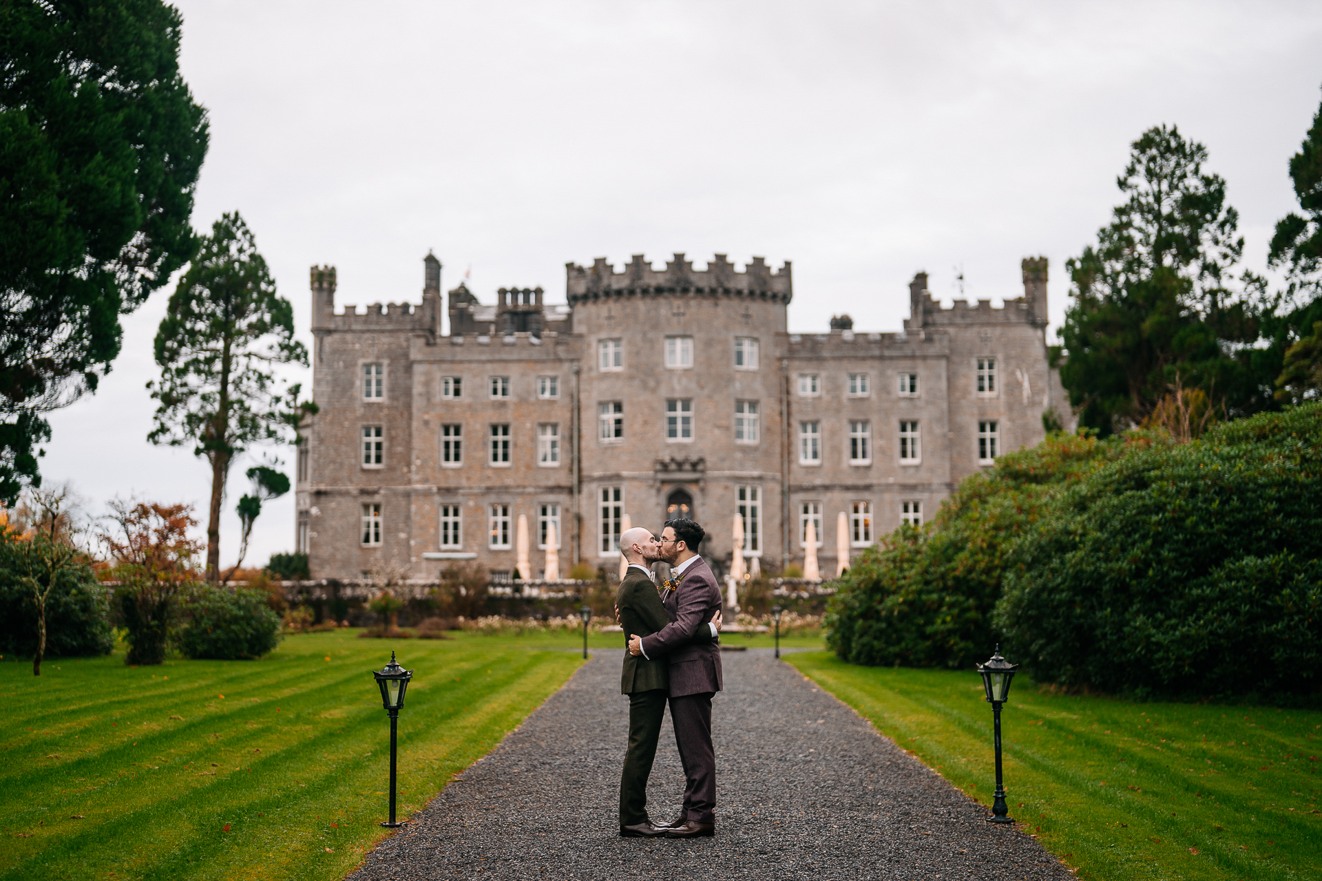 A man and woman kissing in front of a large building