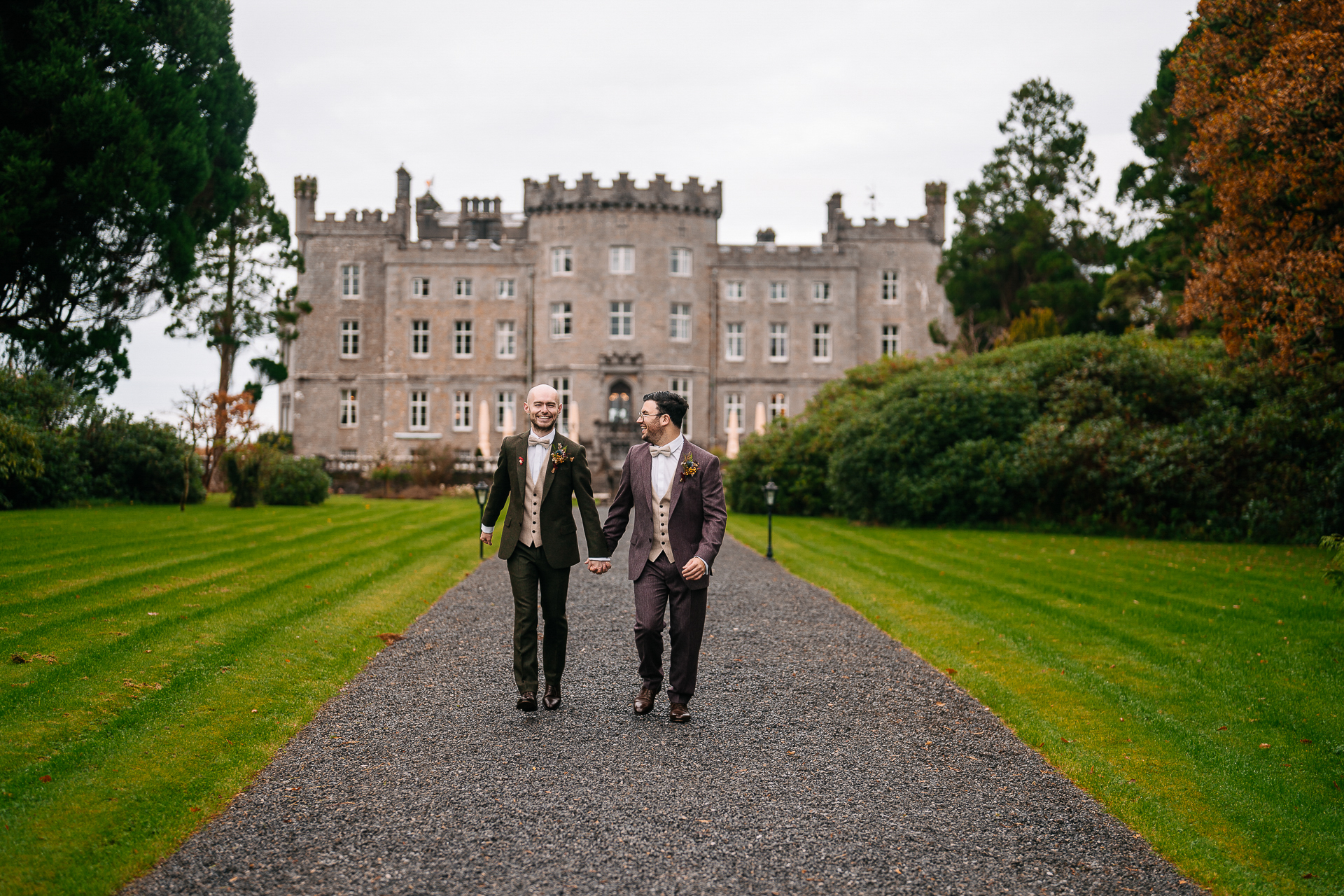 Two men walking on a path in front of a large building