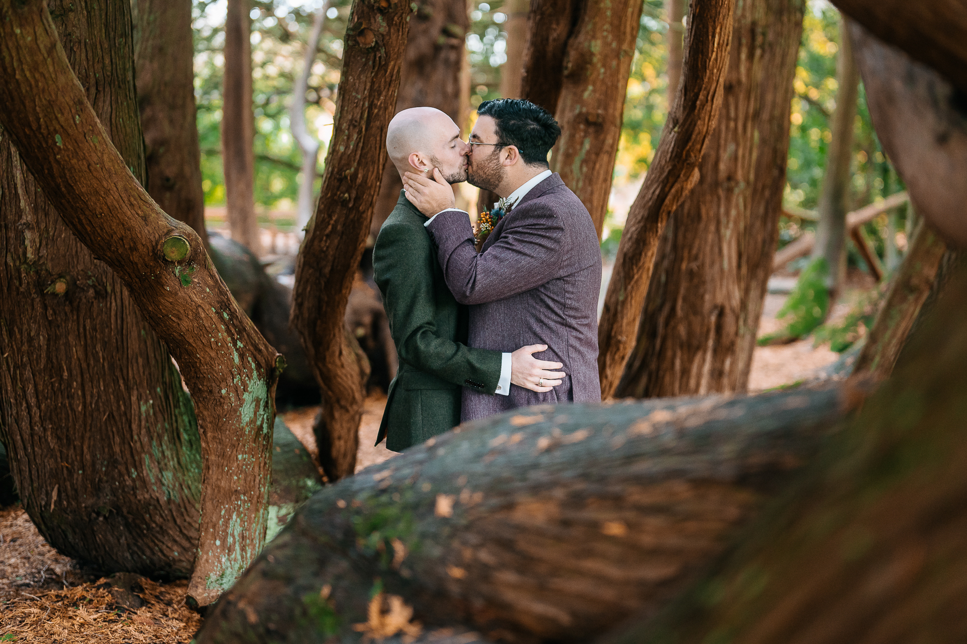 A man and woman kissing in a forest