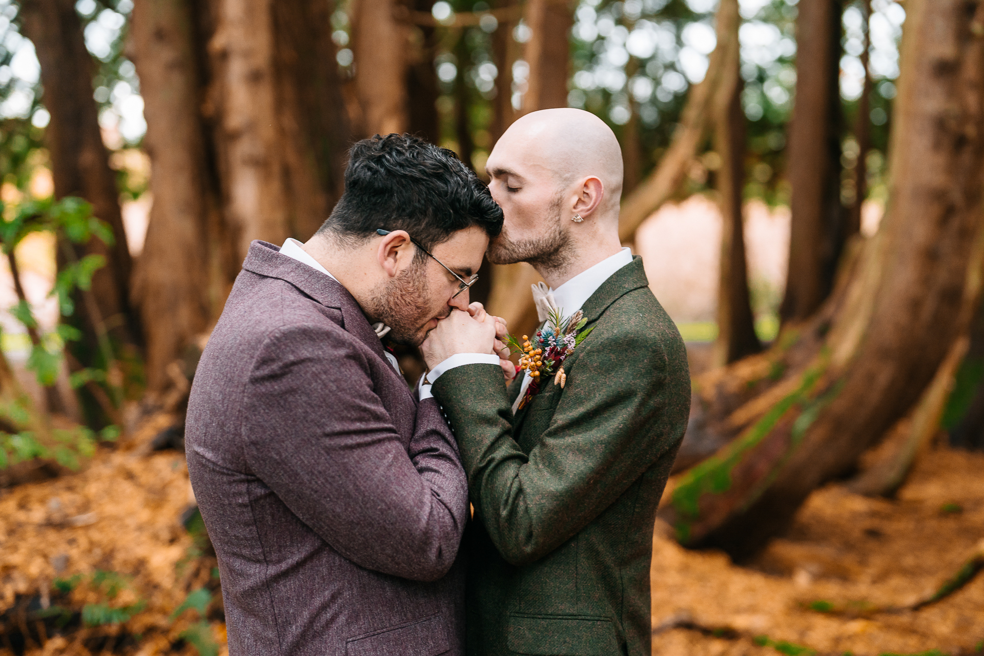 A man kissing another man on the cheek in the woods