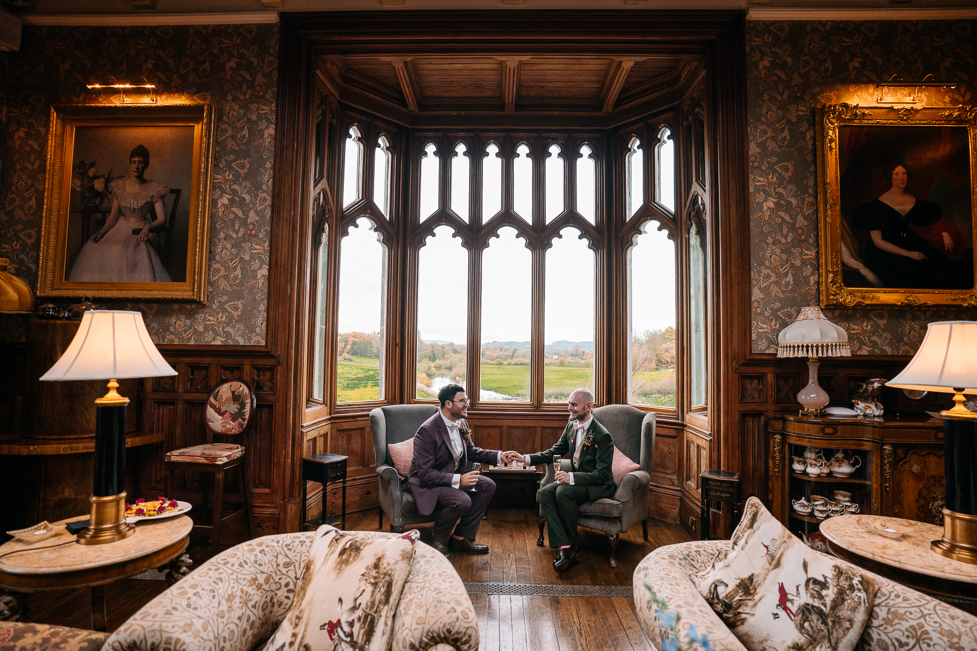 A couple of men sitting on a couch in a room with a large window