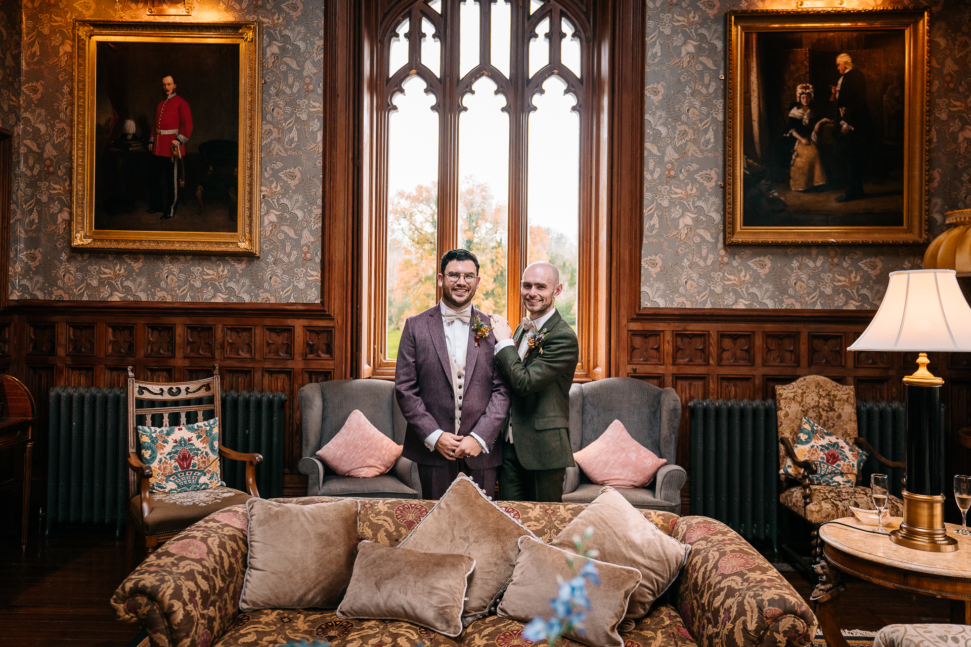 A couple of men in suits standing in a room with a large window