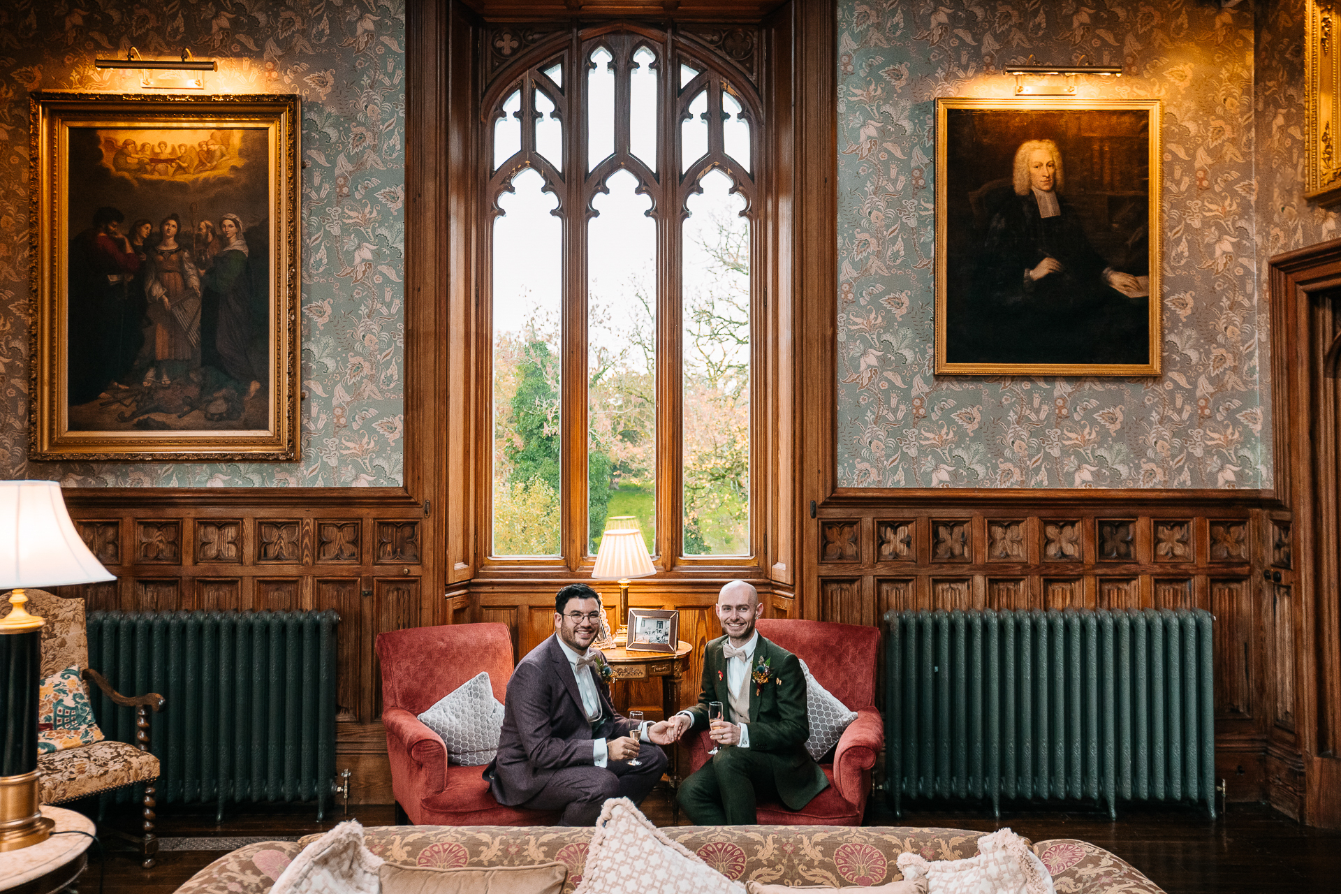 A couple of men sitting on a couch in a room with art on the wall