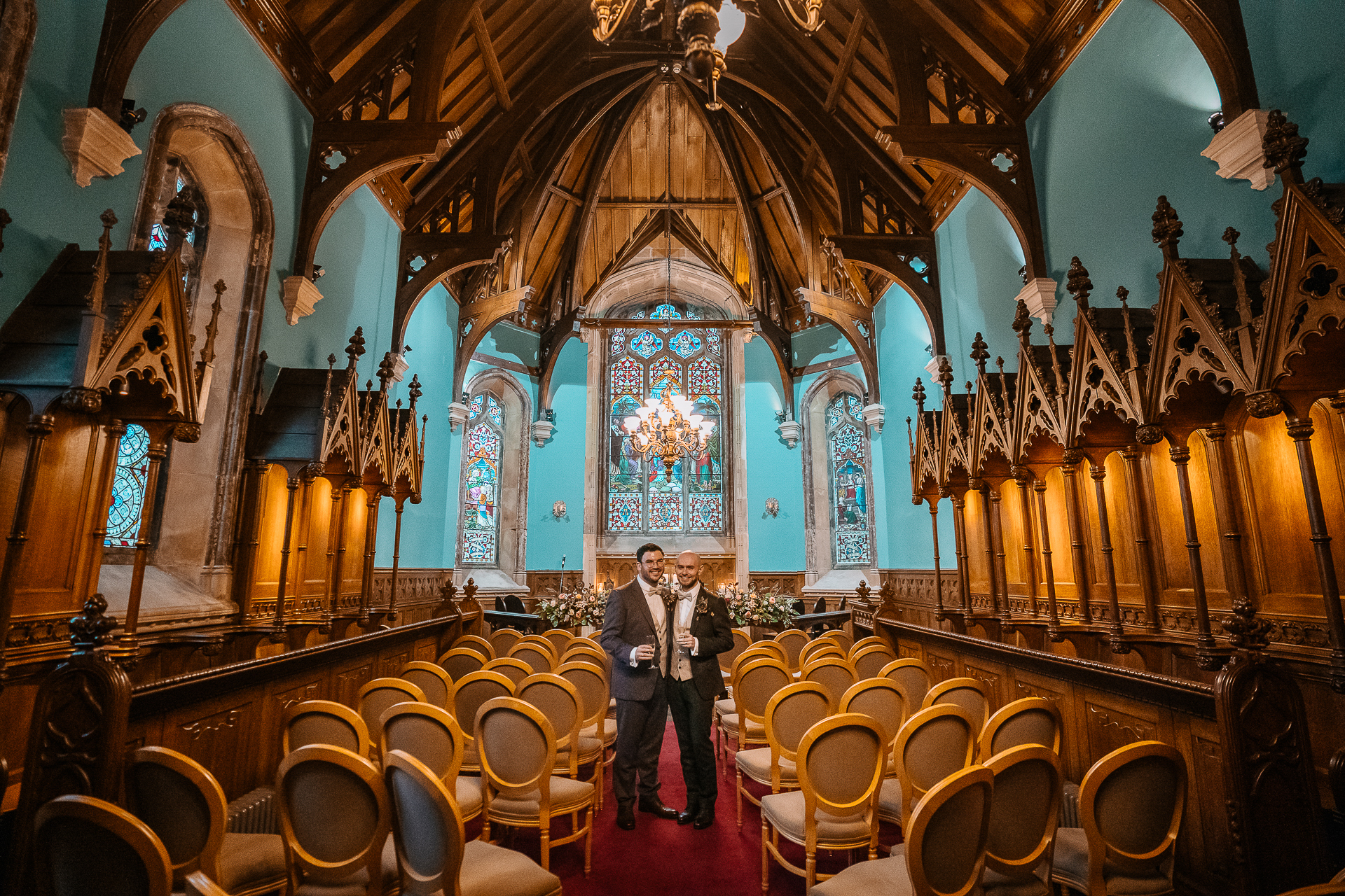 A man and woman standing in a large room with chairs and a large chandelier