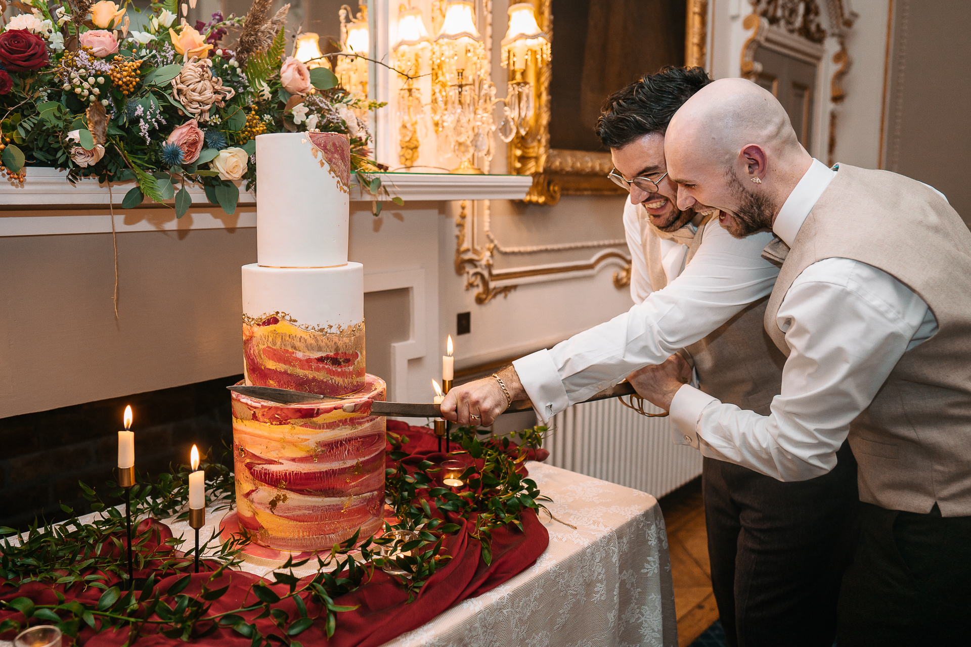 A couple of men cutting a cake