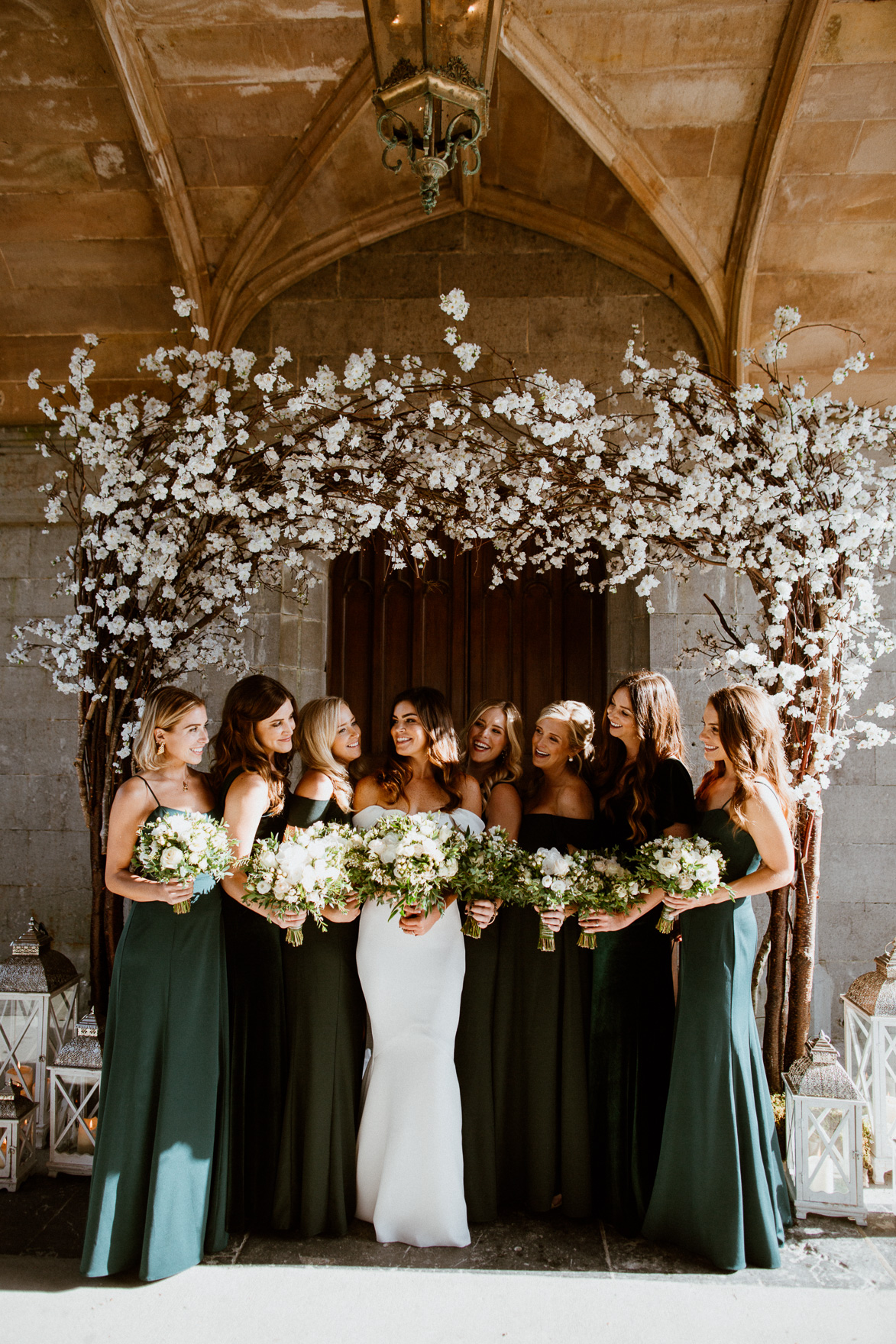 bride with bridesmaids in green dresses standing in front of a building at markree castle wedding 