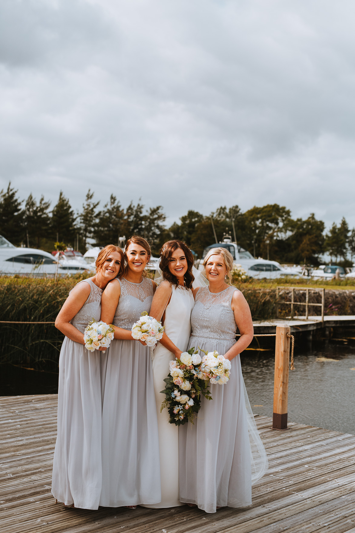 Bride with bridesmaids posing in hotel or fitting room at wedding day.  Bridesmaids help bride to wear wedding dress. long plume in the dress Stock  Photo | Adobe Stock