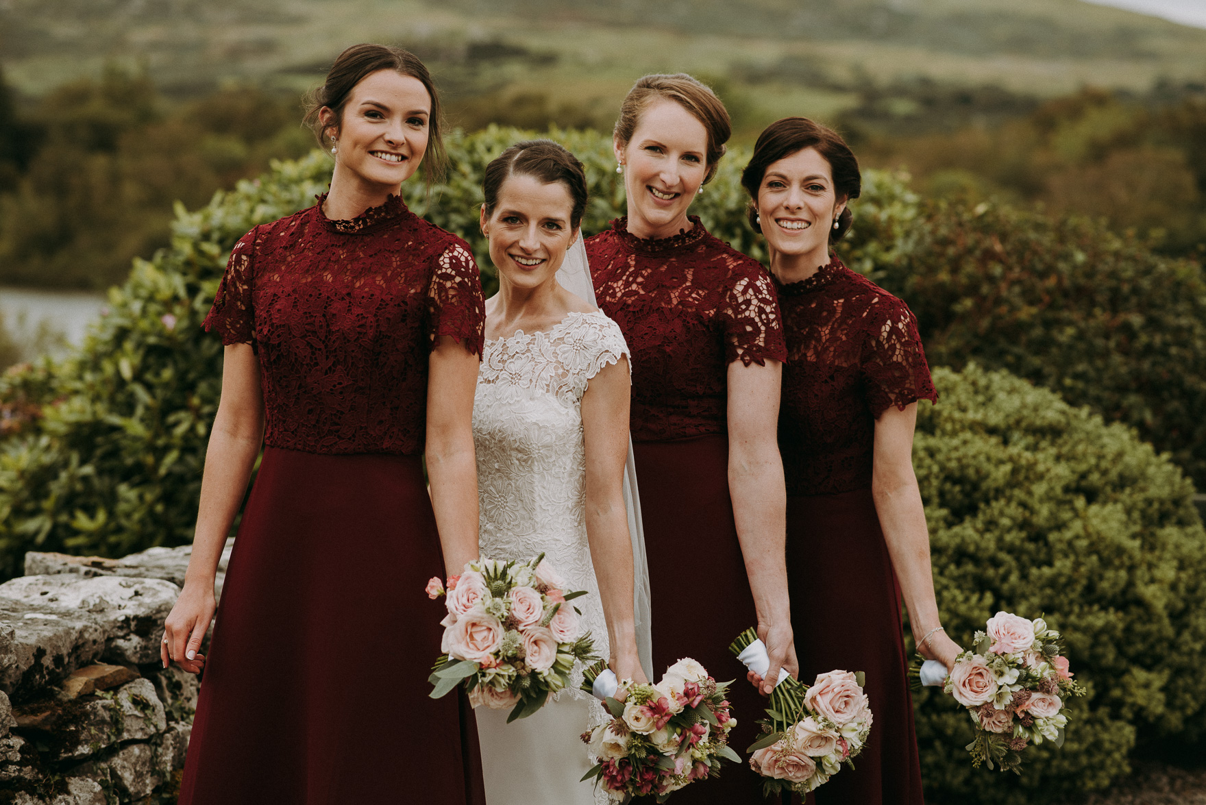 bride and bridesmaids in red dresses in the garden during irish wedding 