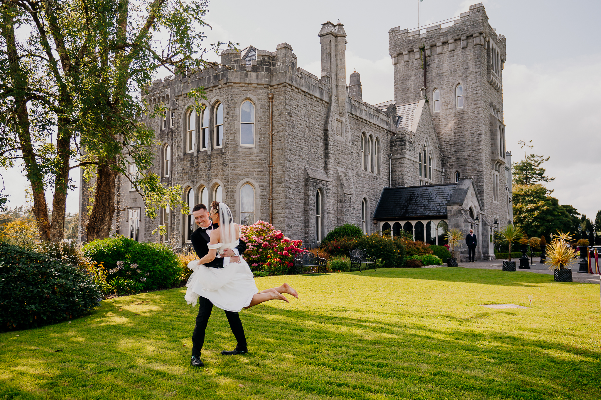 Bride and groom posing on the lawn in front of Kilronan Castle in County Roscommon, Ireland.