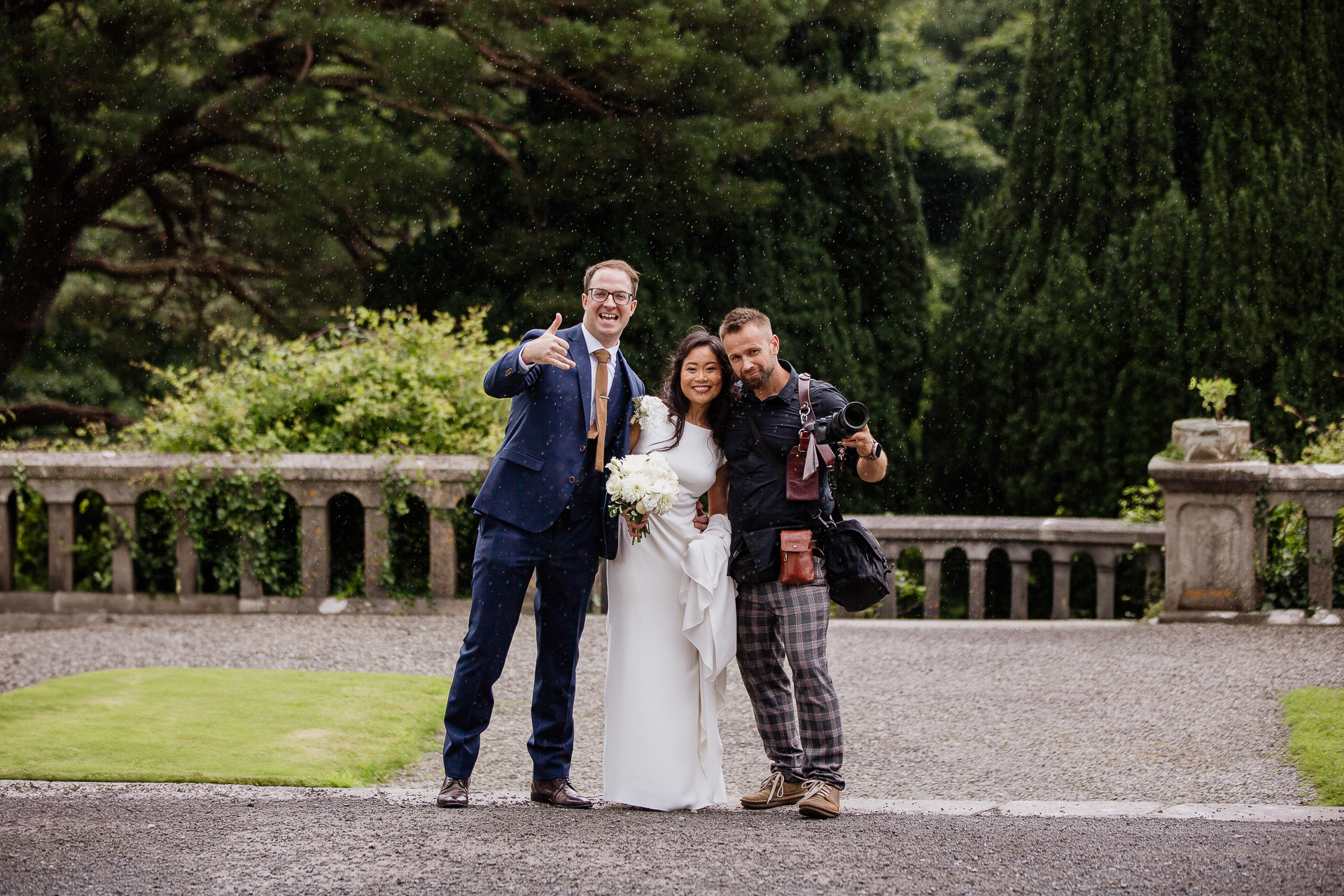 Castle wedding photographer Wojciech Koza posing with a newlywed couple in the gardens of an Irish castle.