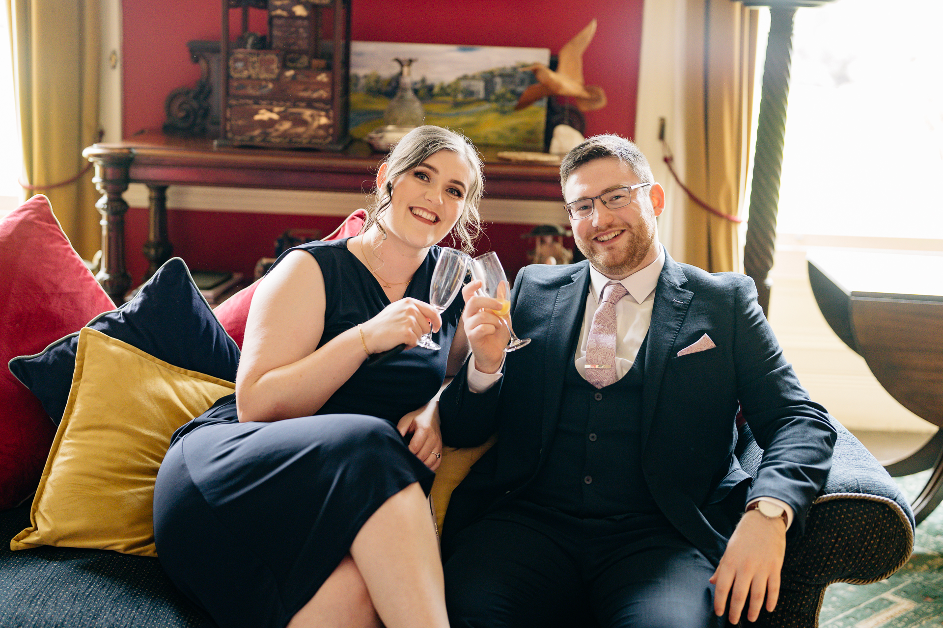 A man and woman sitting on a couch and holding wine glasses