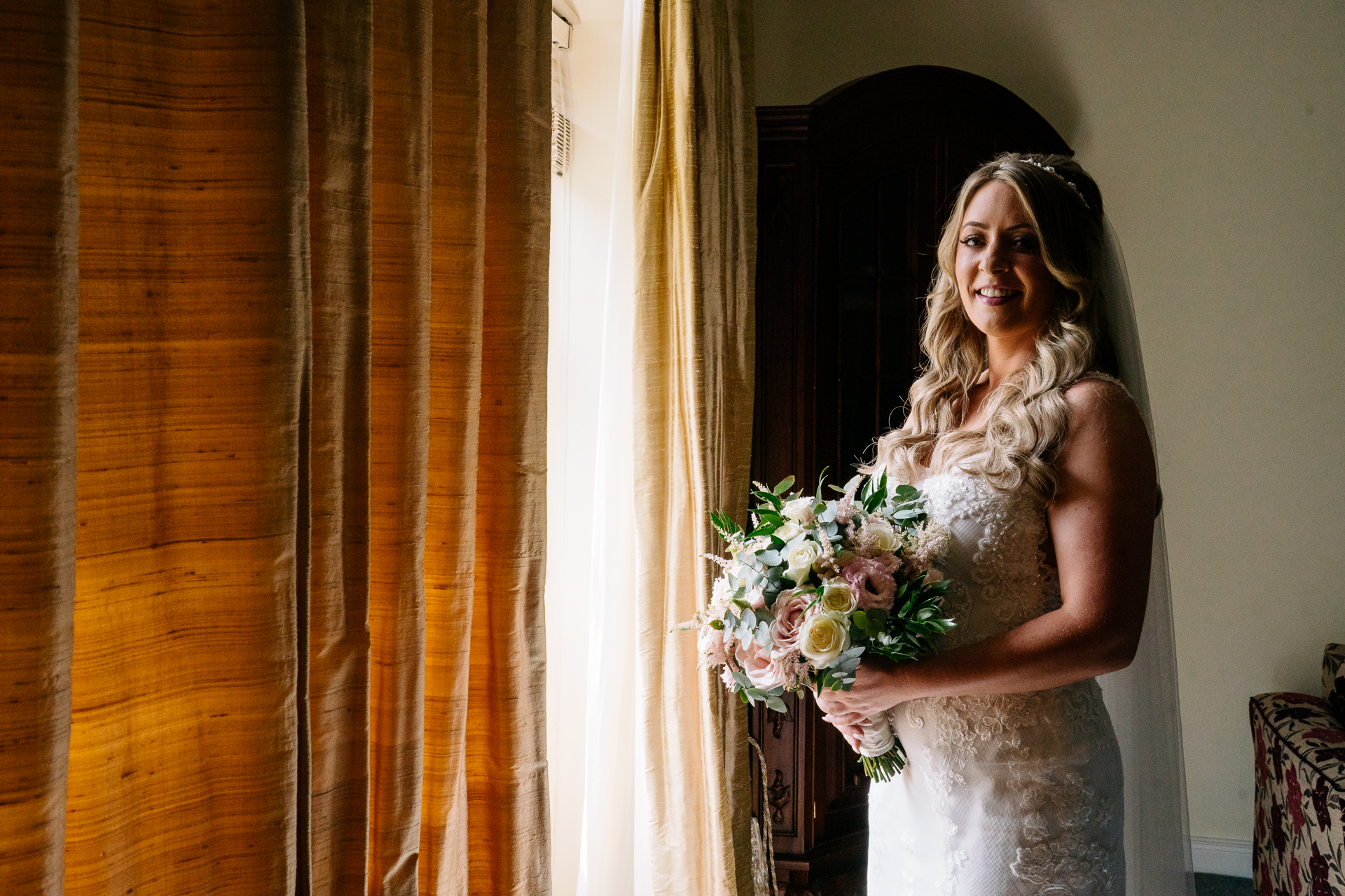 A woman in a wedding dress holding flowers in front of a mirror