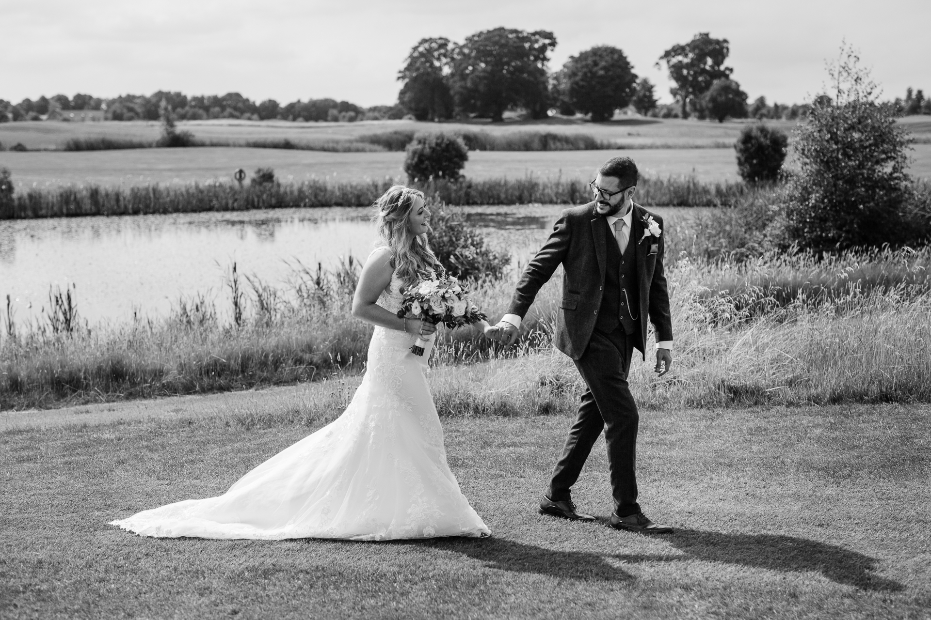 A man and woman walking down a road with a body of water behind them