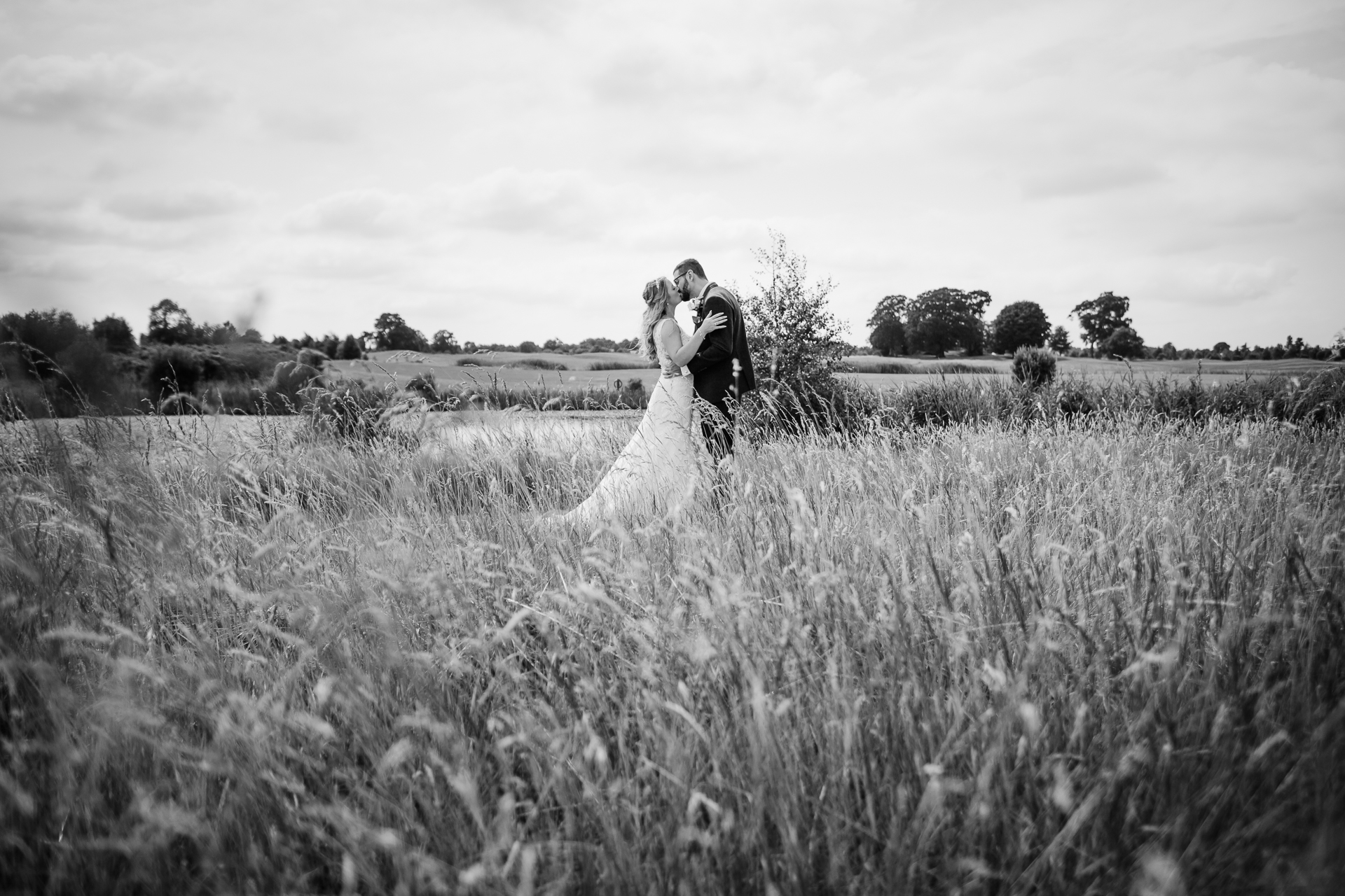 A bride and groom kissing in a field