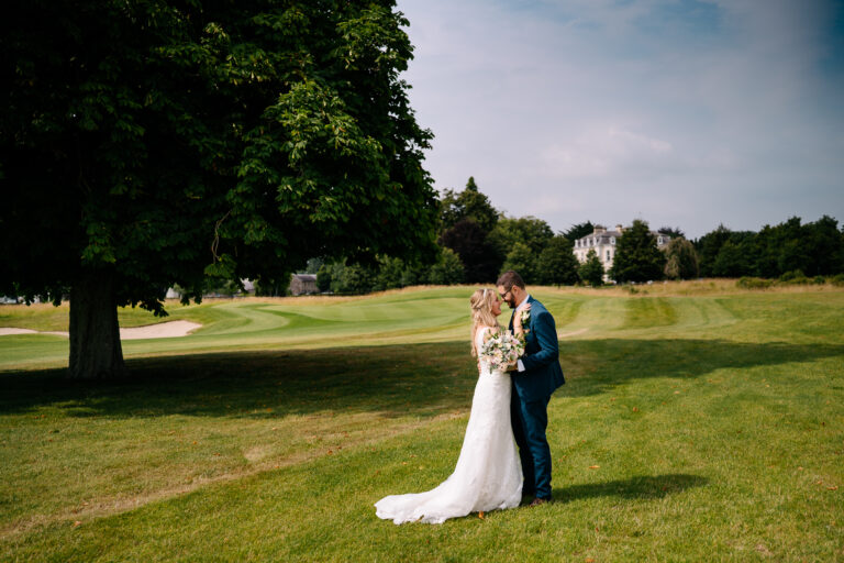 A man and woman in a wedding dress kissing in a grassy field