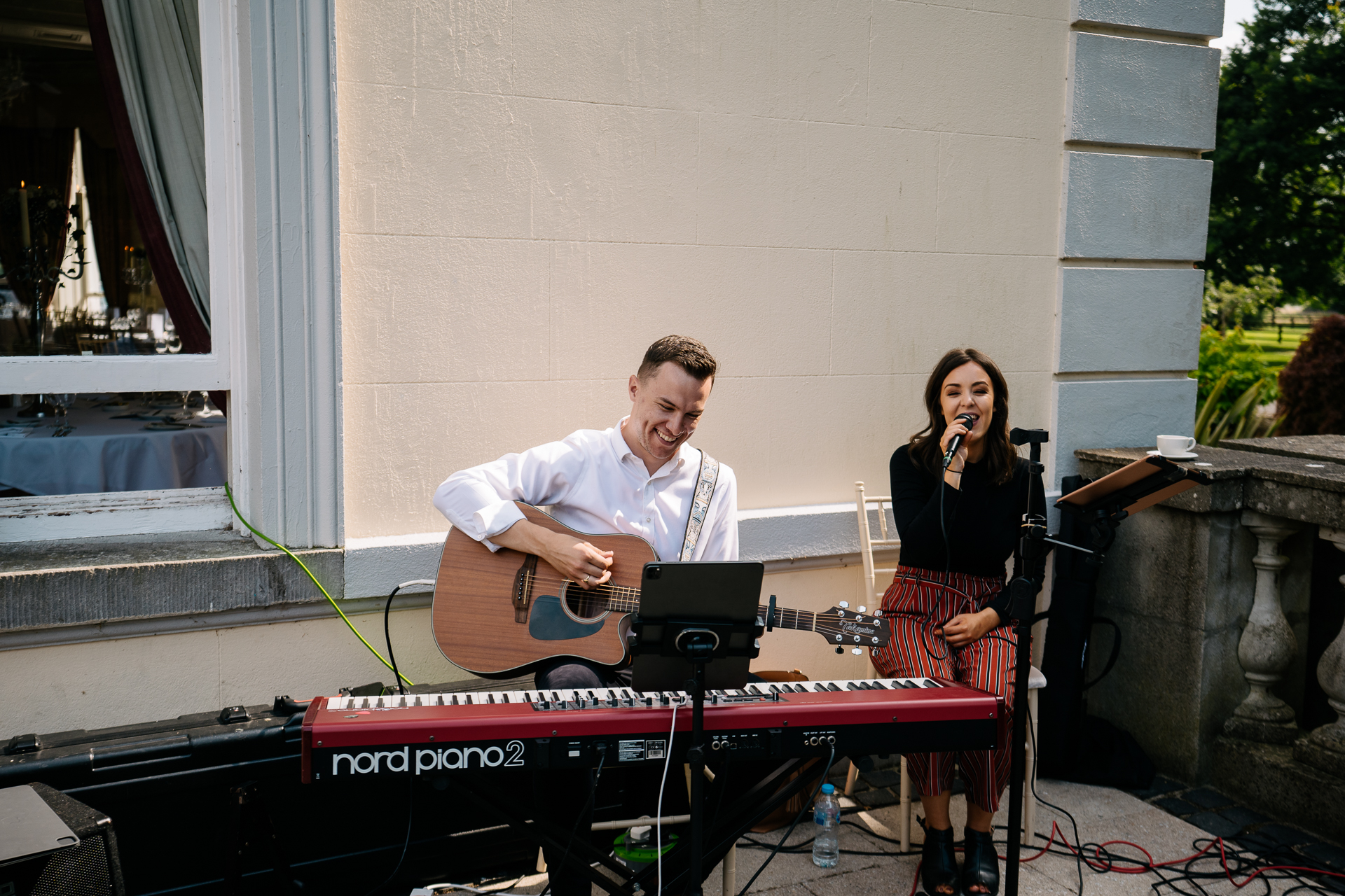 A man playing a guitar next to a woman singing on a stage