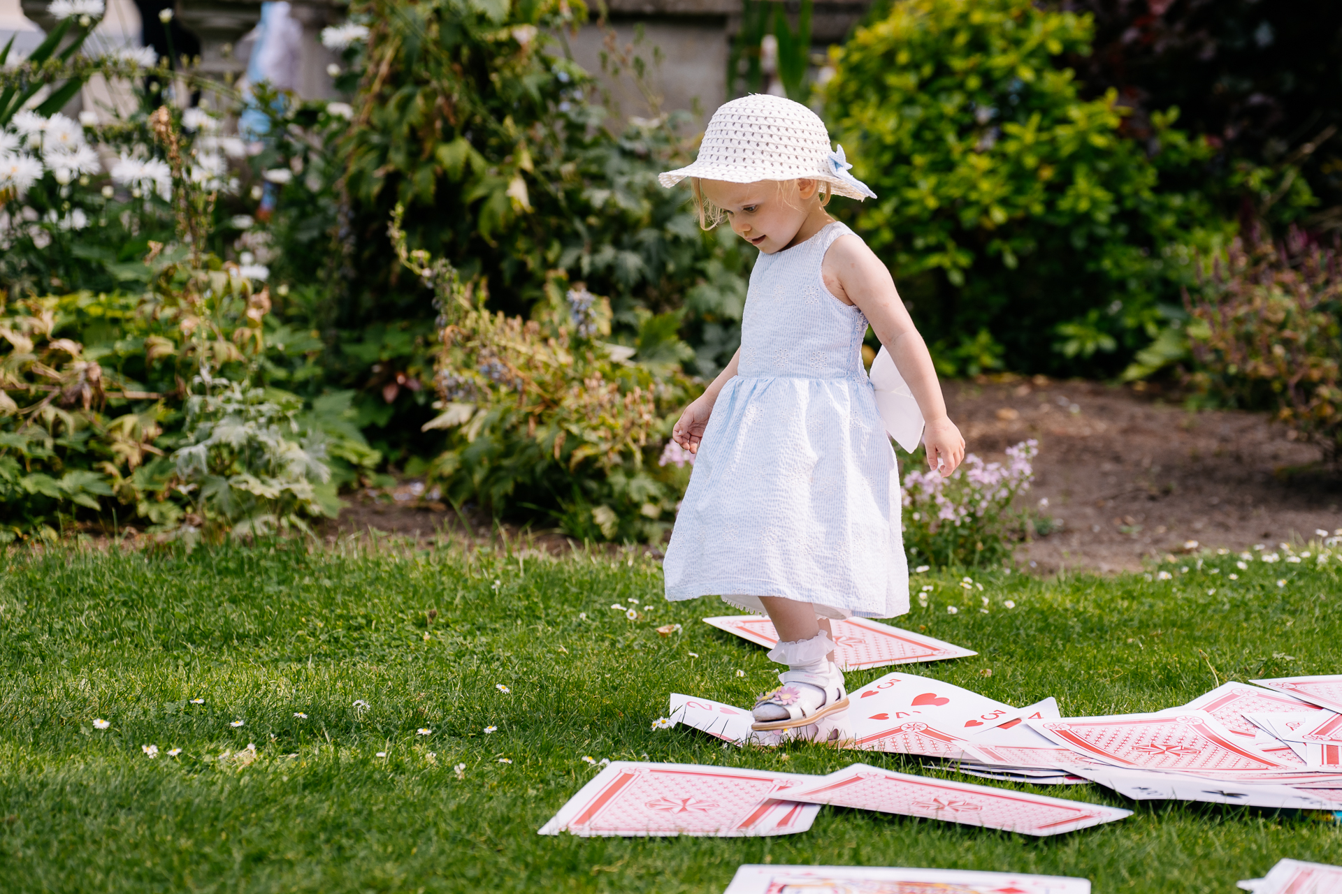 A little girl in a dress standing on a blanket in a yard