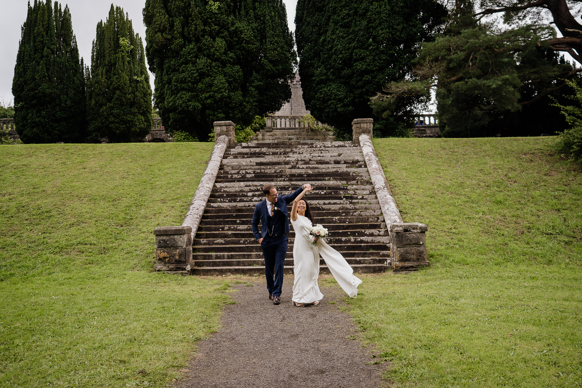 A man and woman walking down a path with a fountain in the background