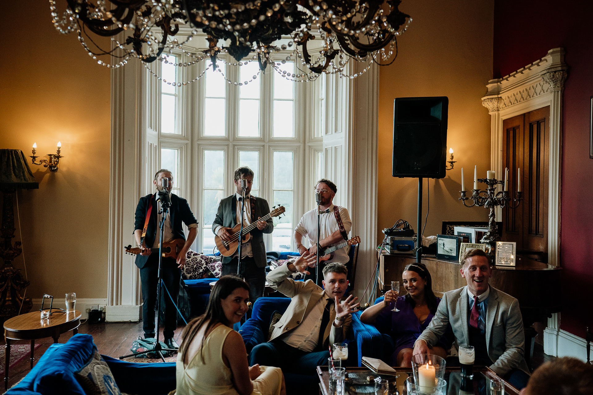 A group of people in a living room with a person playing guitar