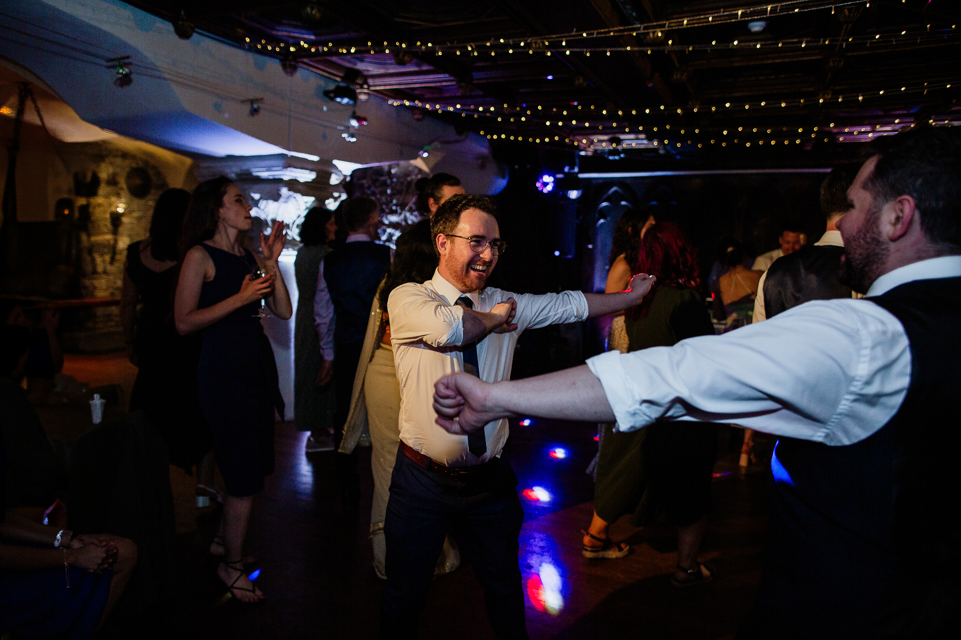 A man holding a woman's hand in a room full of people