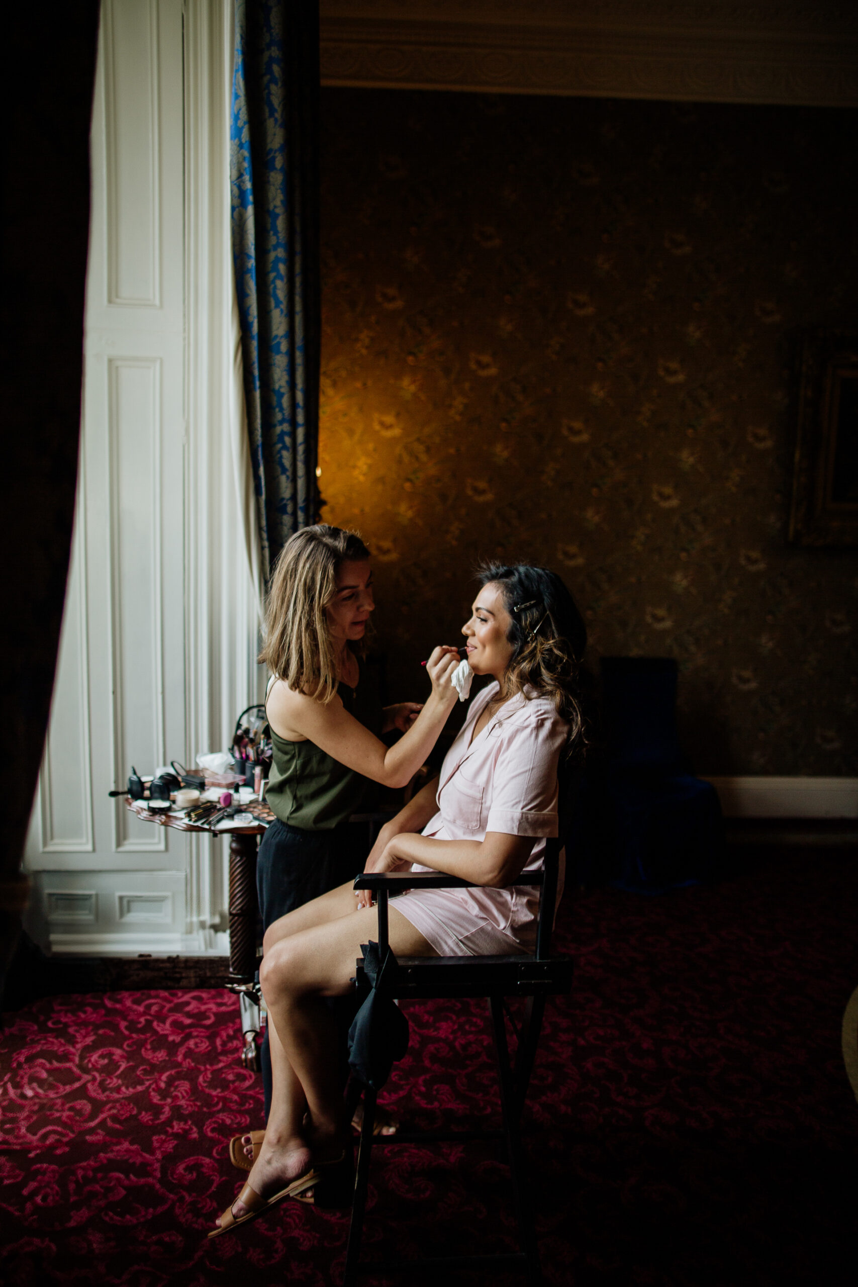 A woman sitting on a chair next to a woman holding a microphone