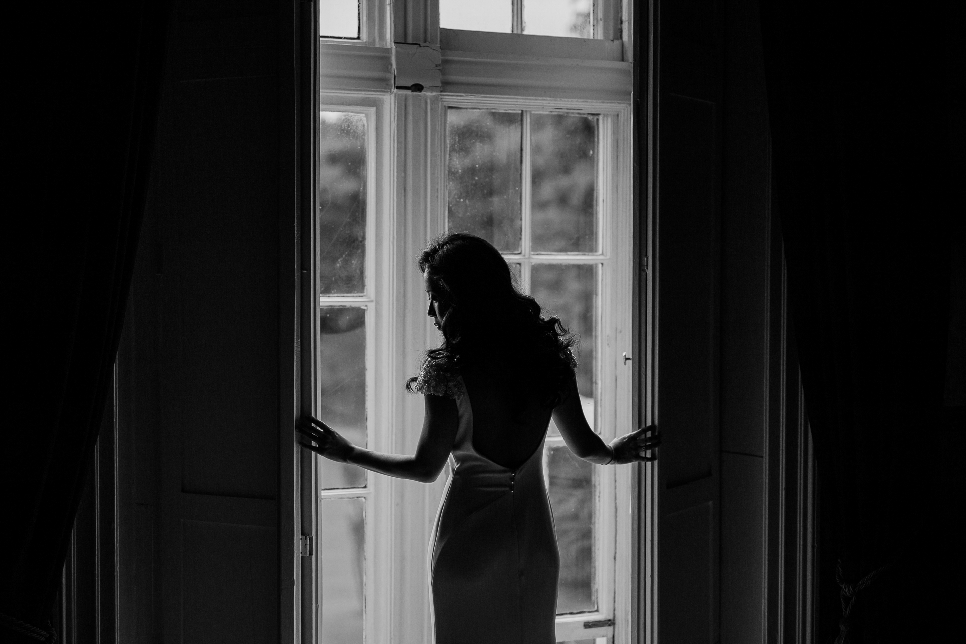 A person in a dress looking out a window