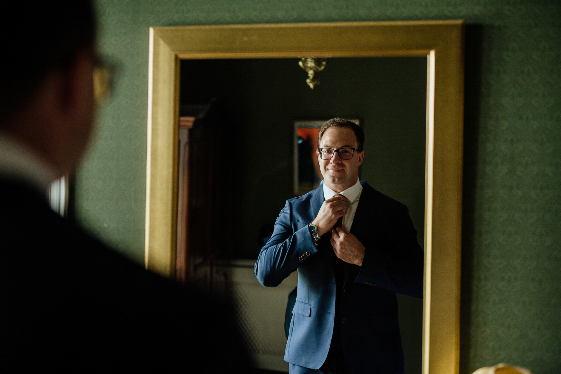 A man in a suit adjusting his tie