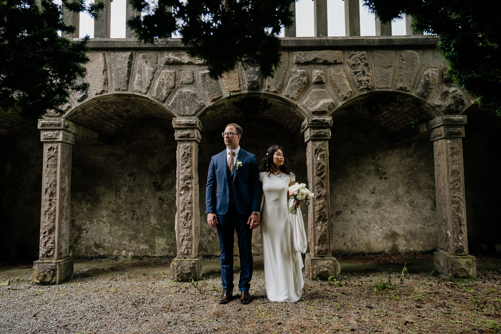 A man and woman posing for a picture in front of a stone arch