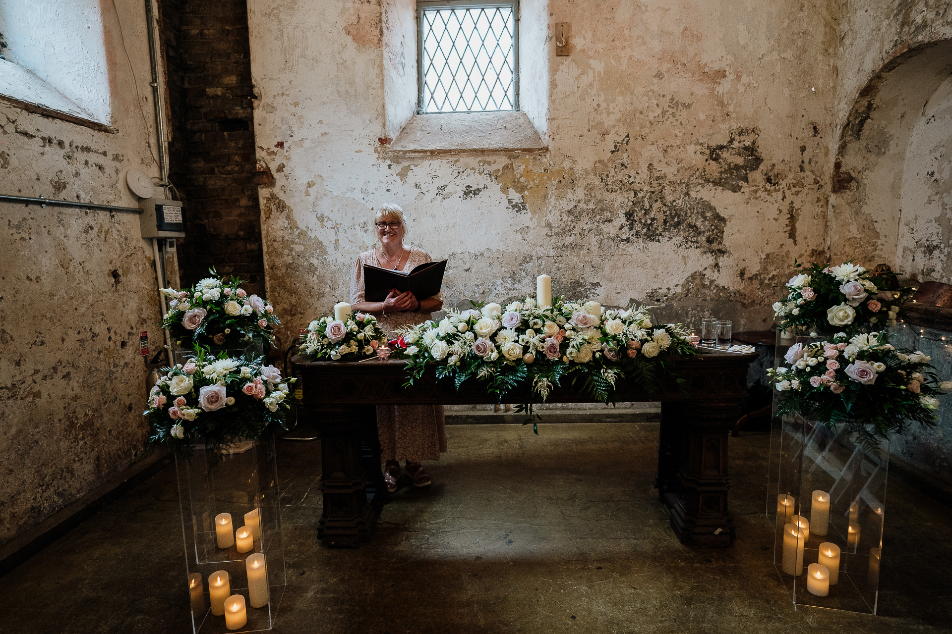 A person sitting at a table with flowers and candles