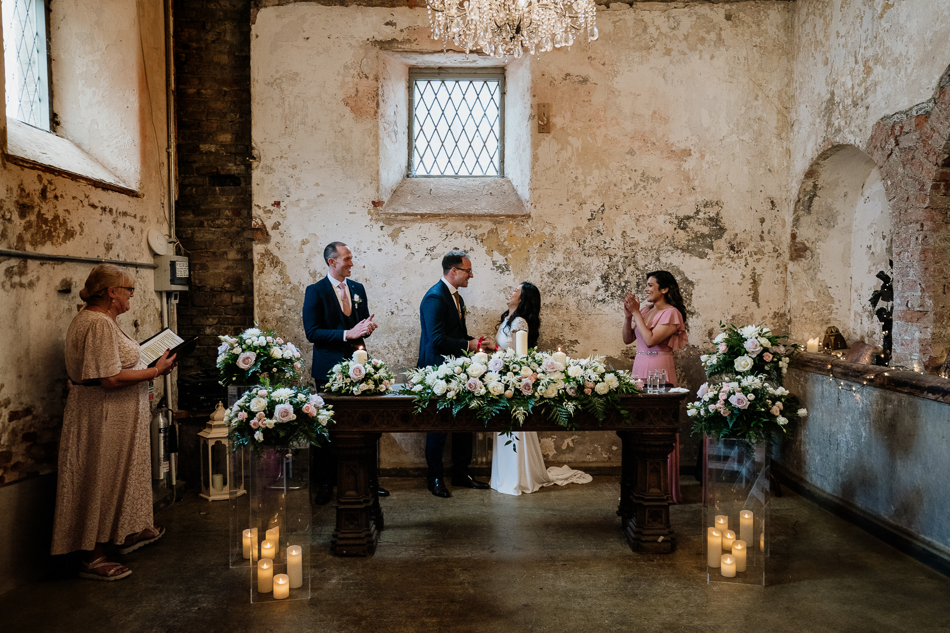 A group of people standing around a table with flowers and candles