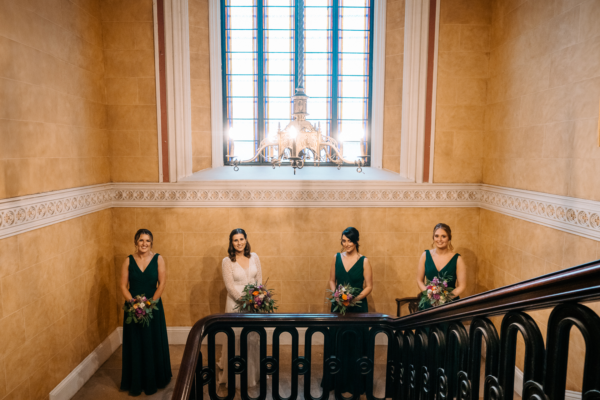 A group of women in dresses standing on a balcony in front of a large window