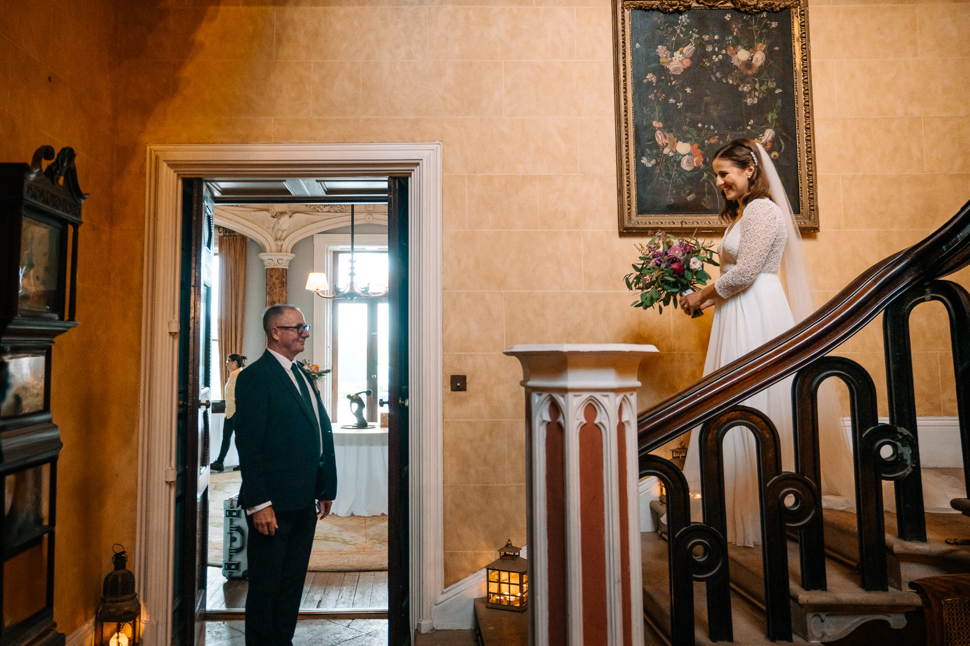 A man and woman standing in a room with a staircase and a painting