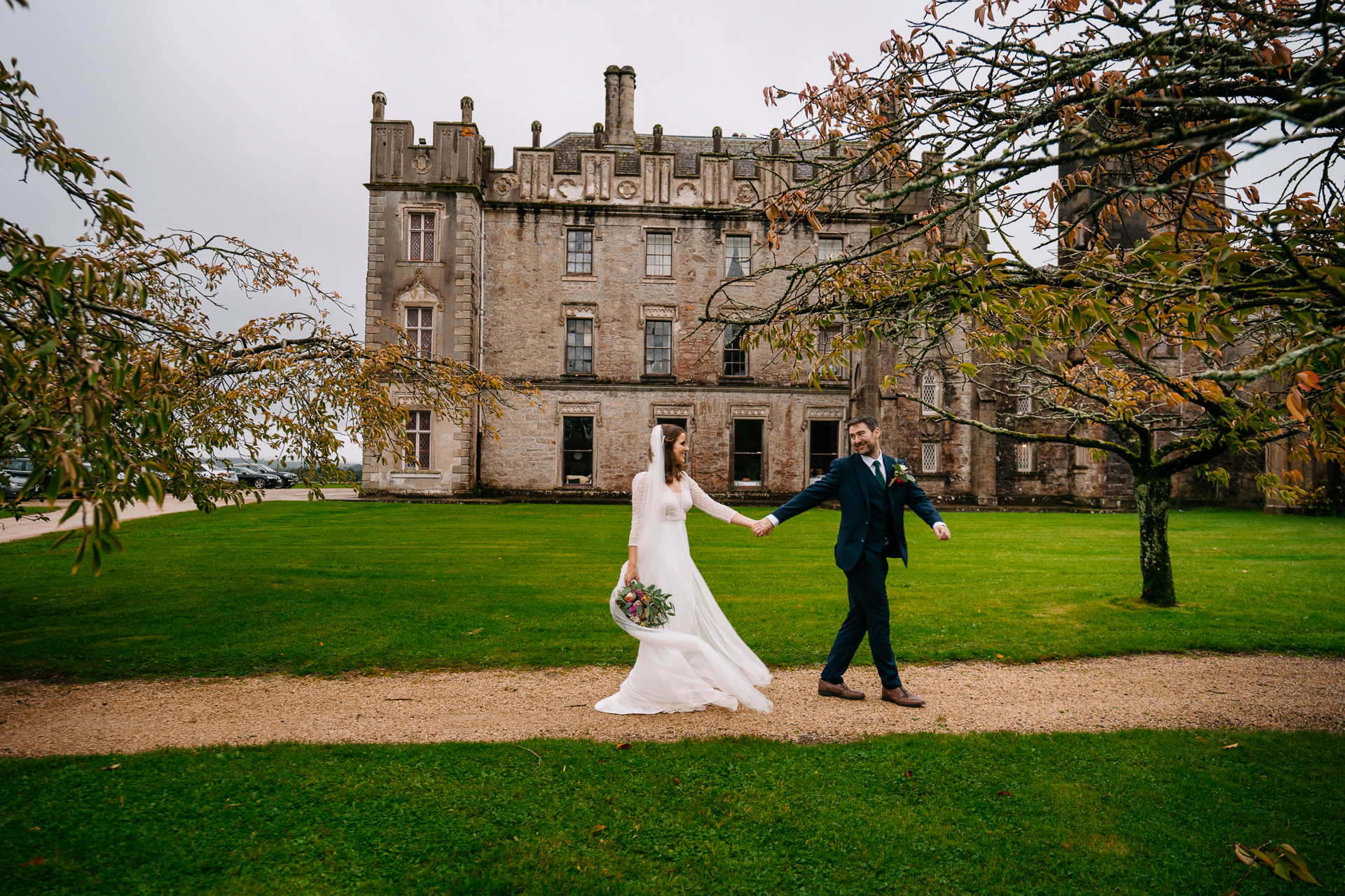 A man and woman in wedding attire walking in front of a large building