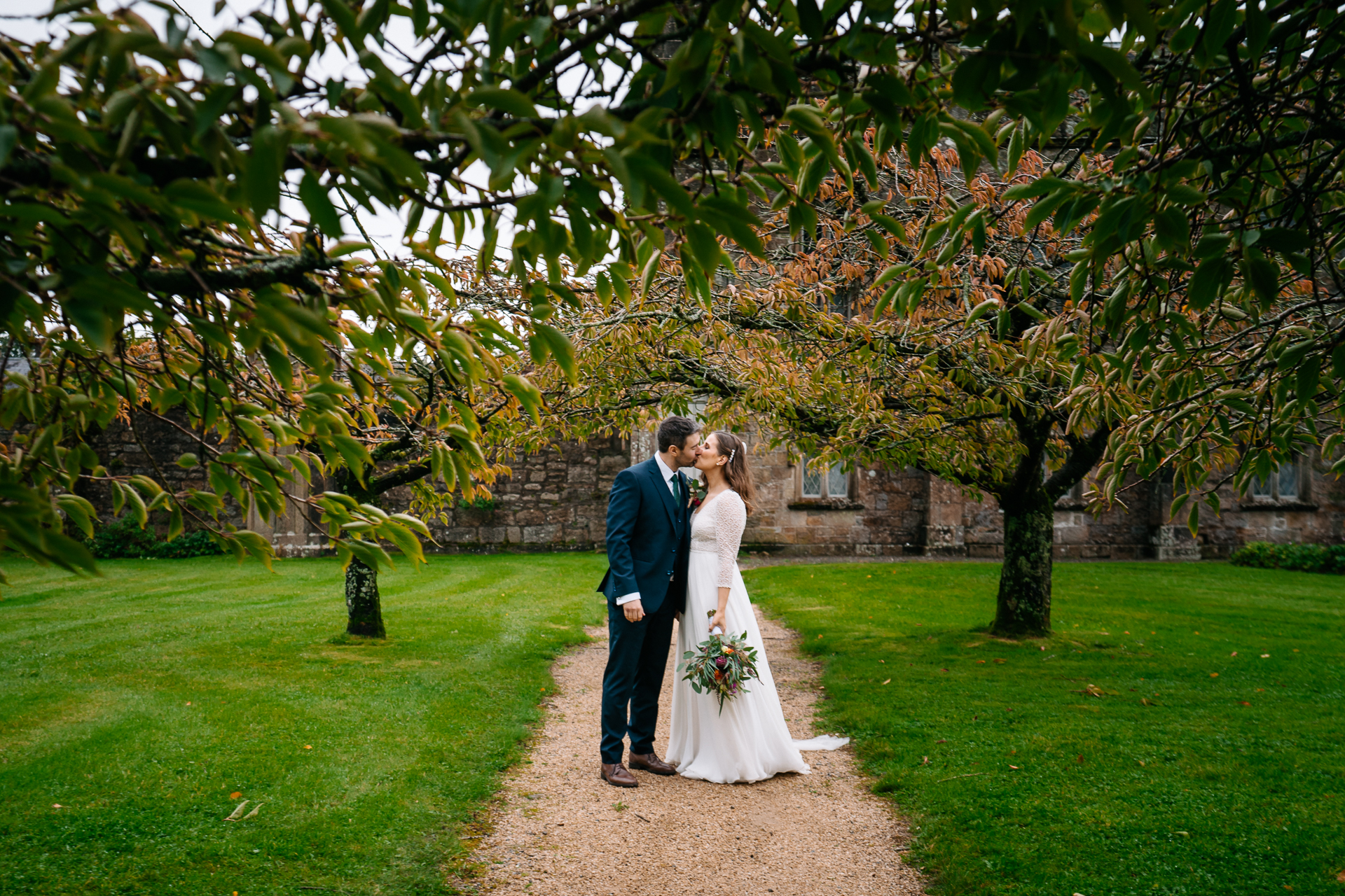 A man and woman walking down a path under a tree