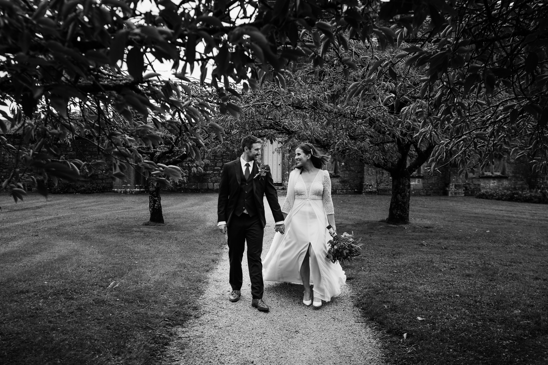 A man and woman walking down a path with flowers