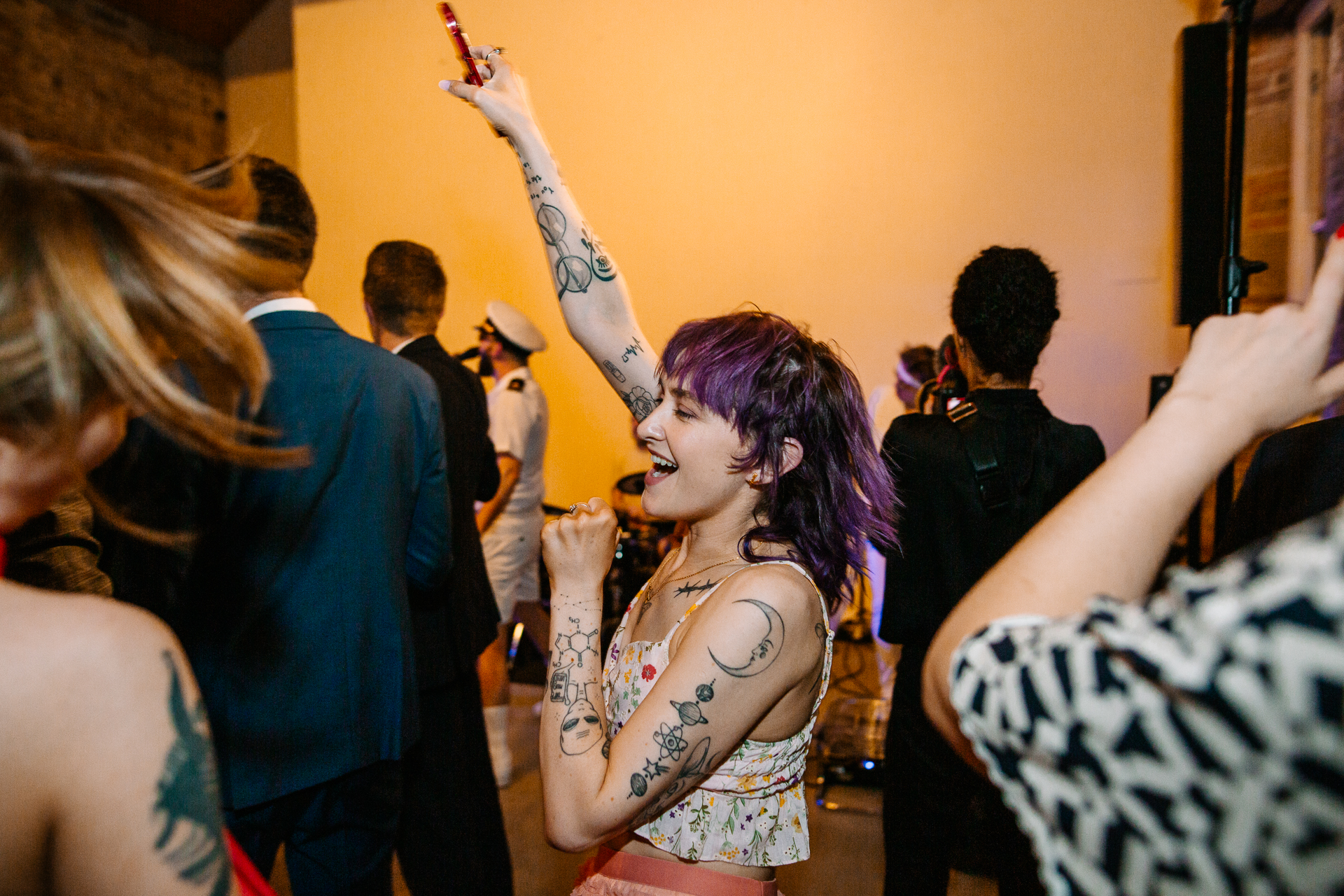 A person with a tattoo on the arm in a room with other people