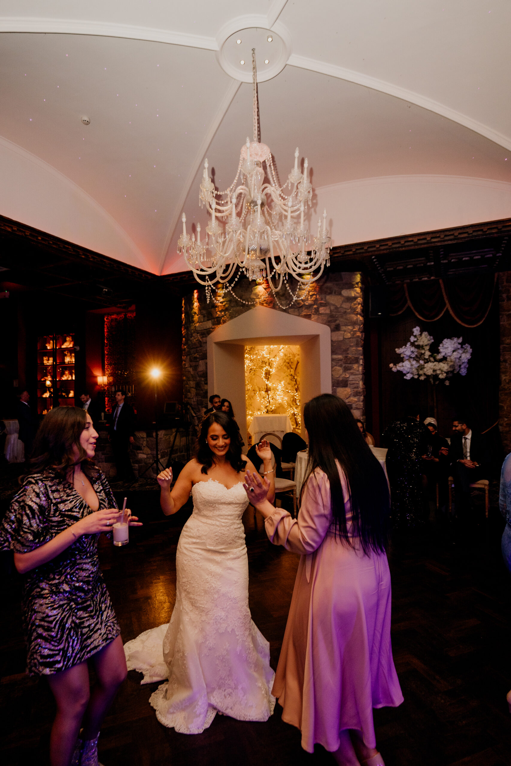 A group of women dancing in a room with chandeliers