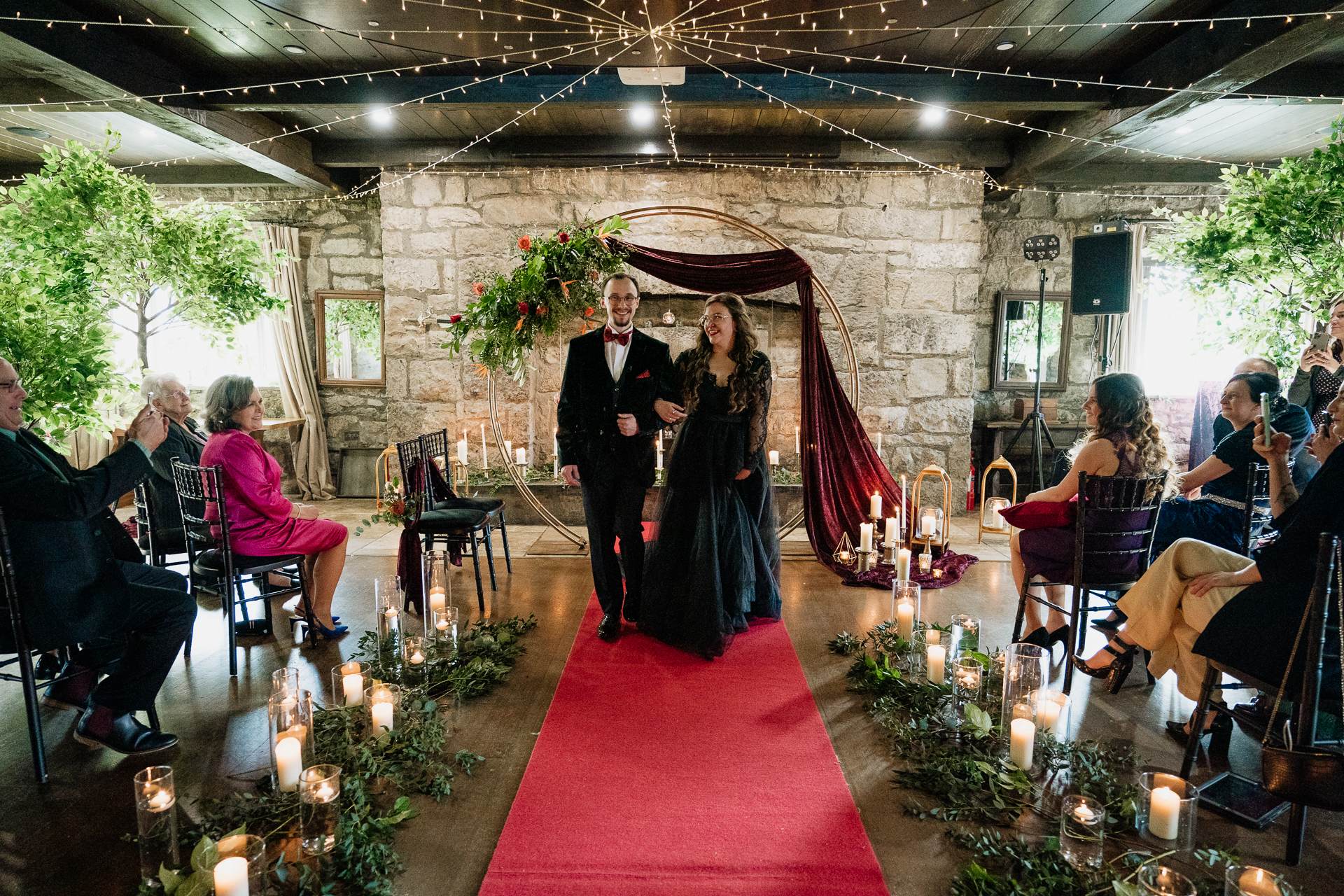 A man and woman walking down a red carpet in a room with people