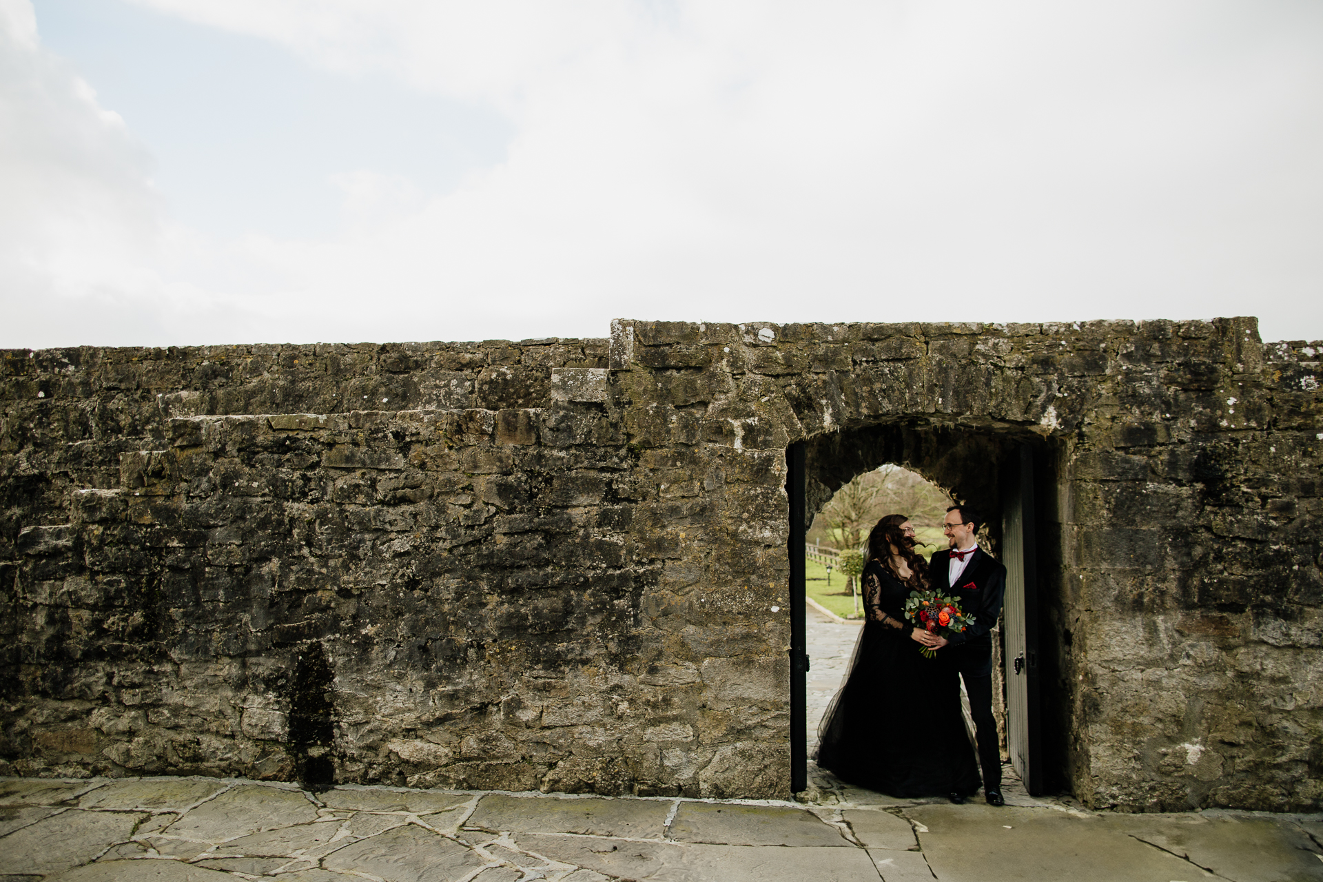 A man and woman kissing in a stone archway