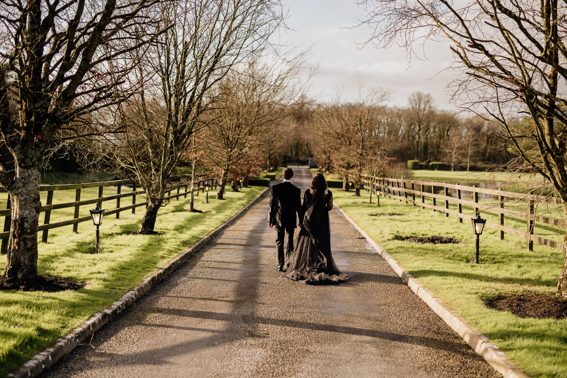 A man and woman kissing on a path with trees on either side