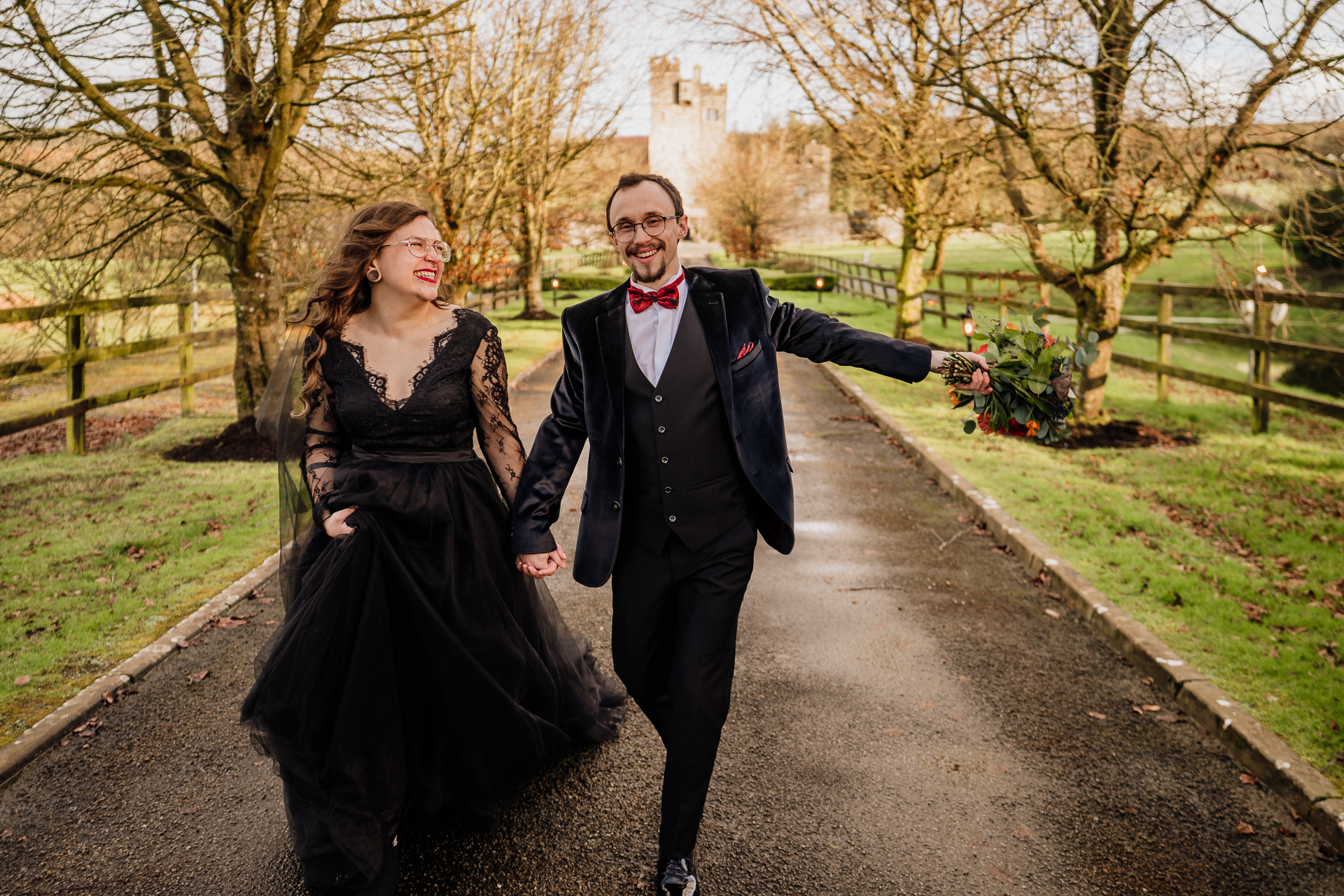 A man and woman walking down a path with flowers and trees