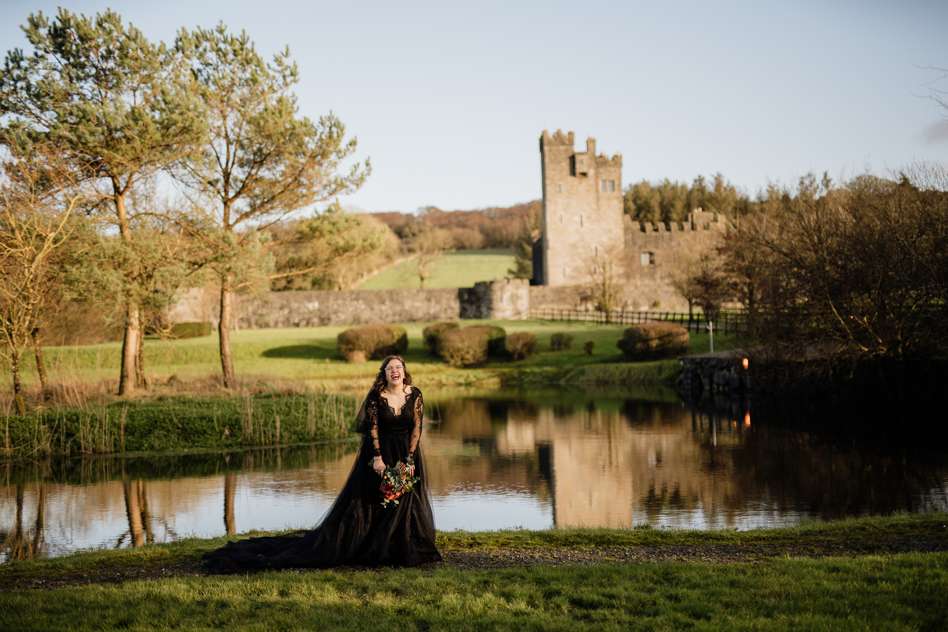 A person in a black dress standing in front of a castle