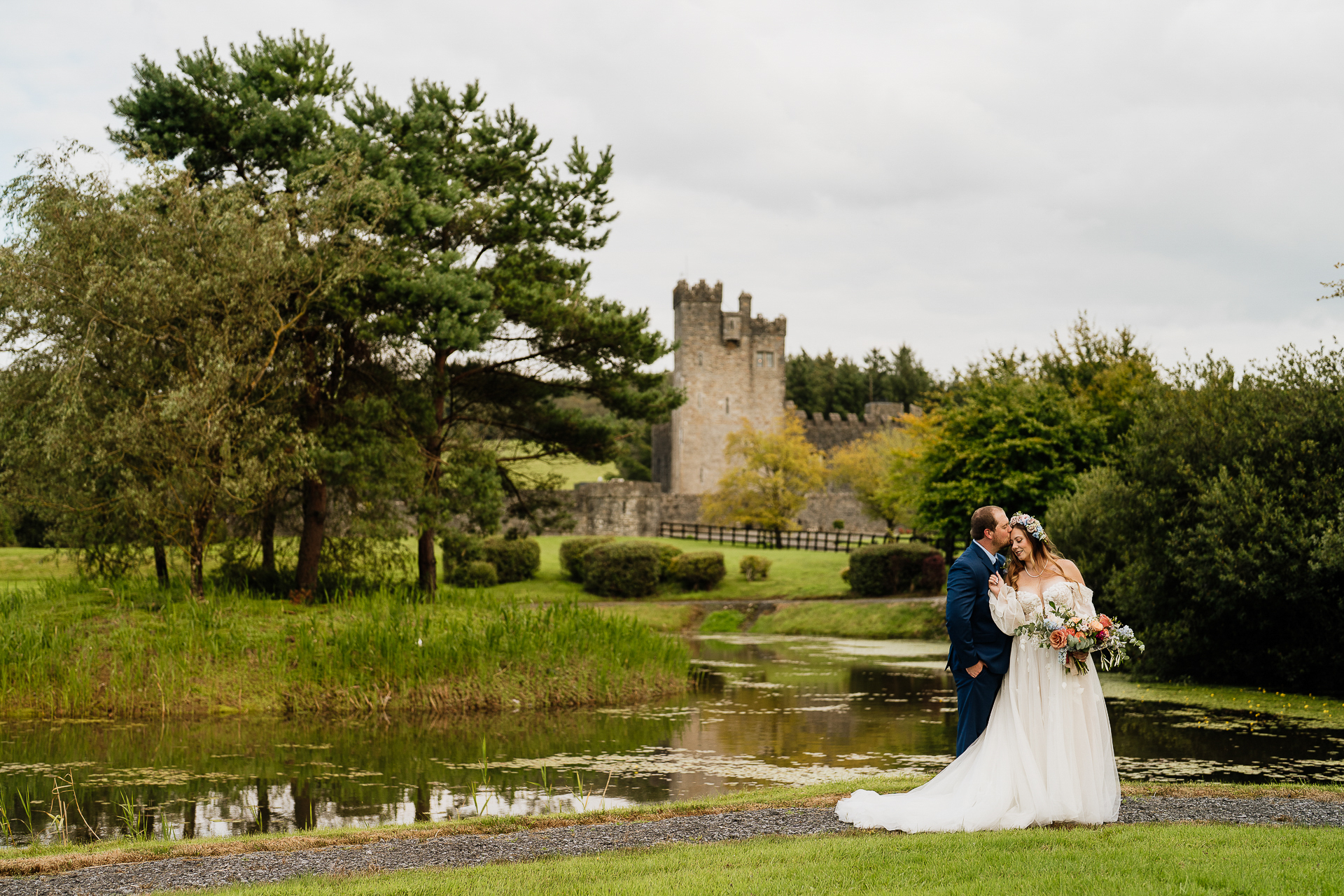 A man and woman kissing in front of a castle