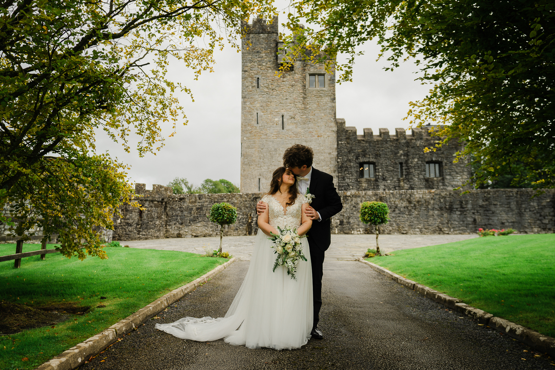 A man and woman kissing in front of a castle