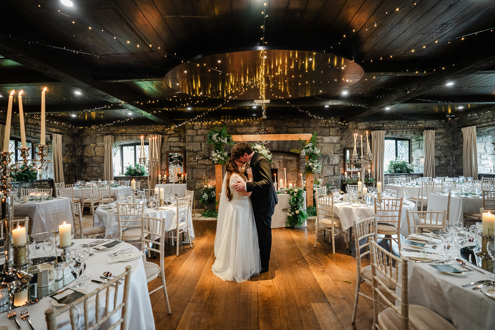 A man and woman kissing in a room with tables and chairs