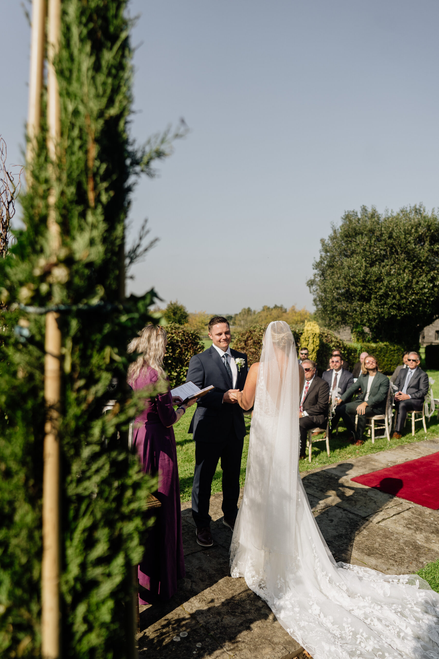 A man and woman walking down a path with a wedding dress and a couple of people sitting on