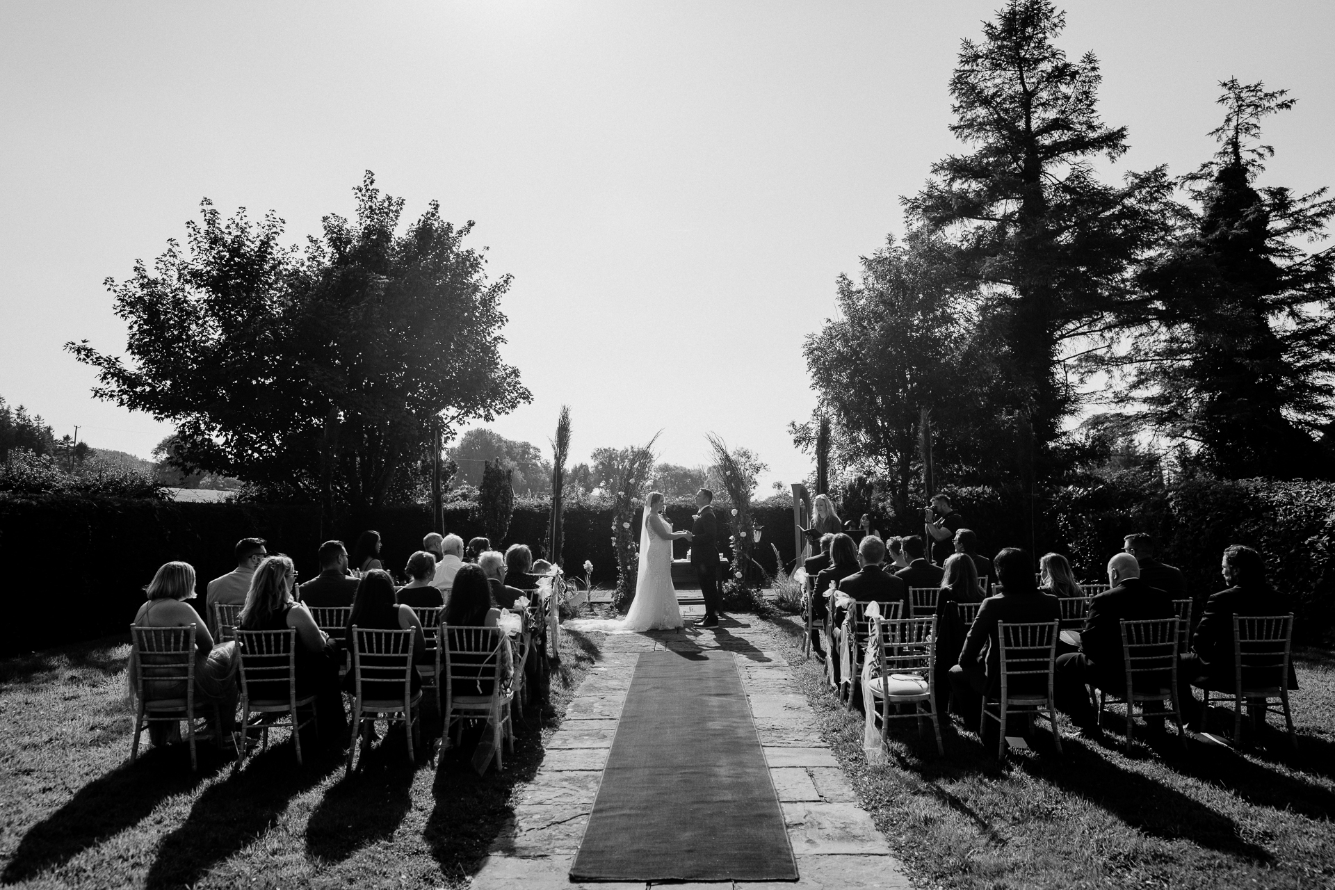 A group of people sitting on a bench watching a wedding