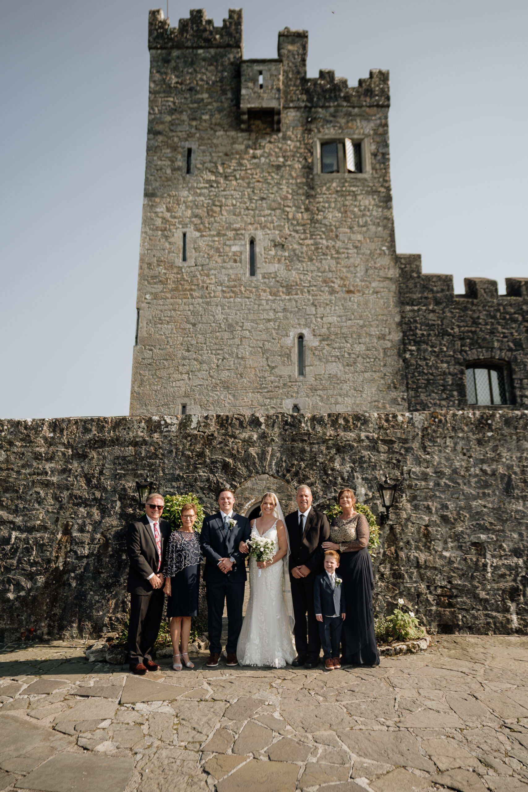 A group of people posing for a photo in front of a stone castle