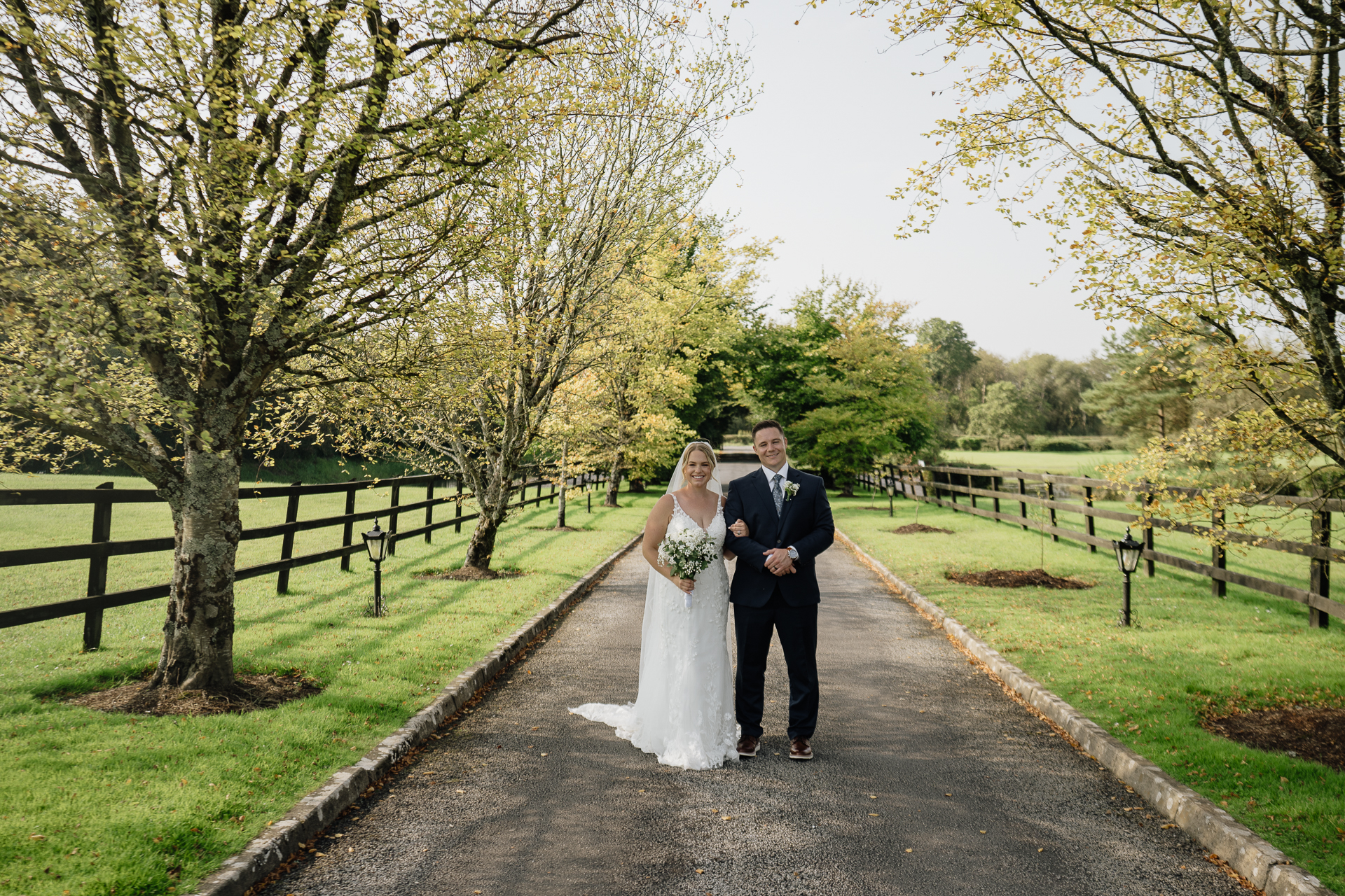 A man and woman posing for a picture on a path with trees